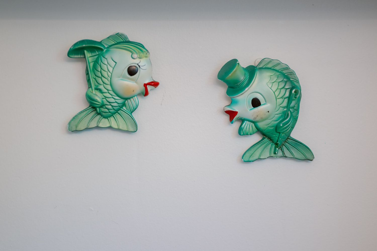 A series of identical green ceramic fish decorations arranged in a row on a white surface.