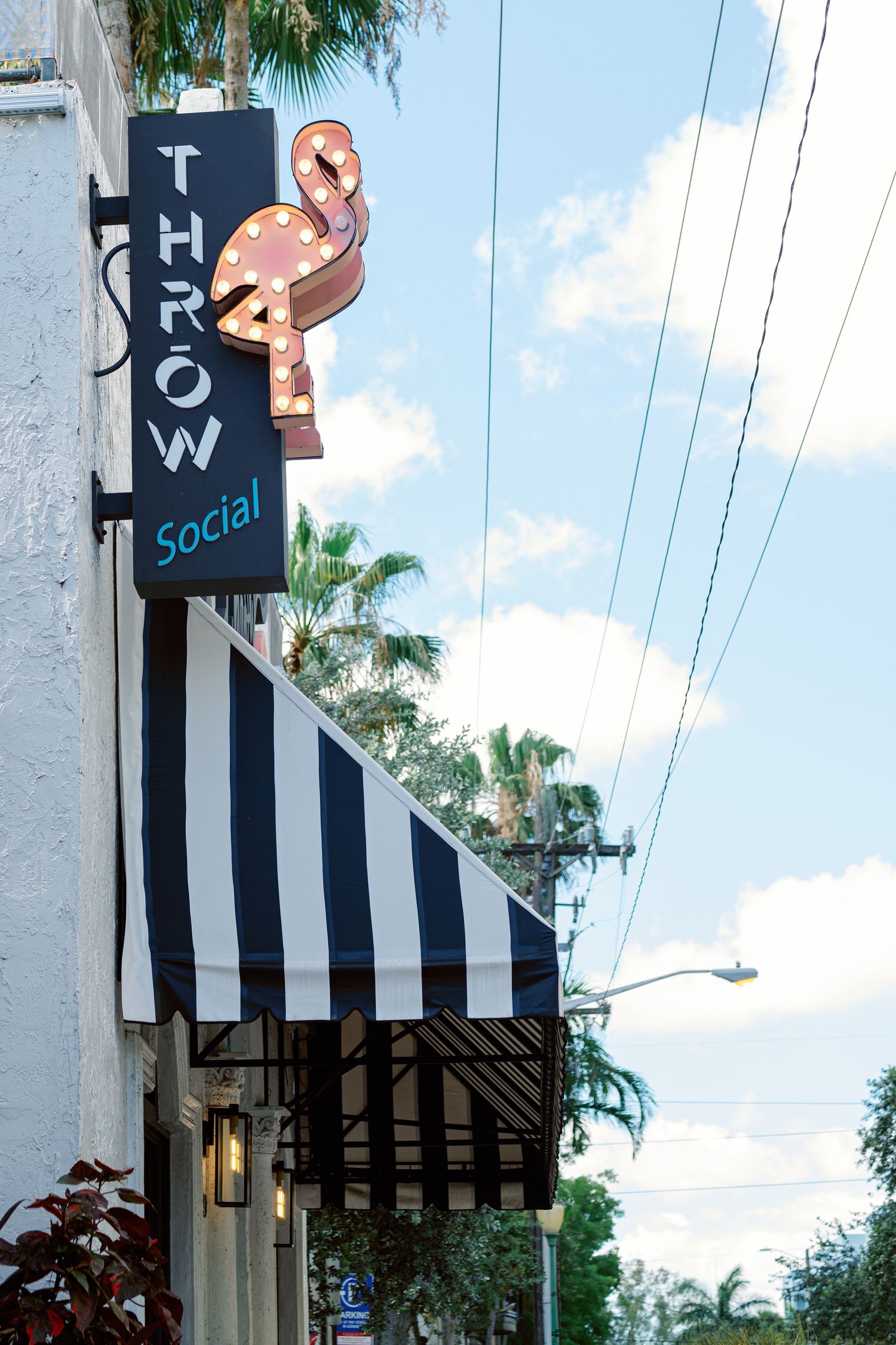 Black and white striped awning with 'THROW' signage on a building exterior against a blue sky with palm trees.