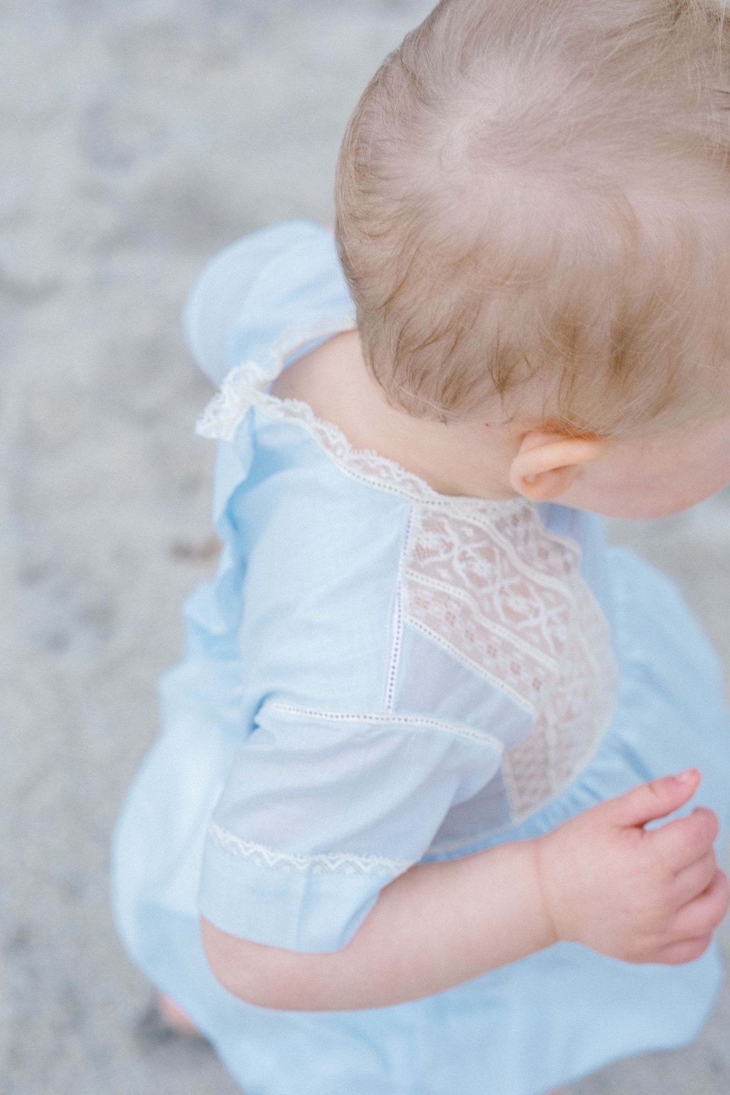 Close up detail of light blue and white lace dress on small child.