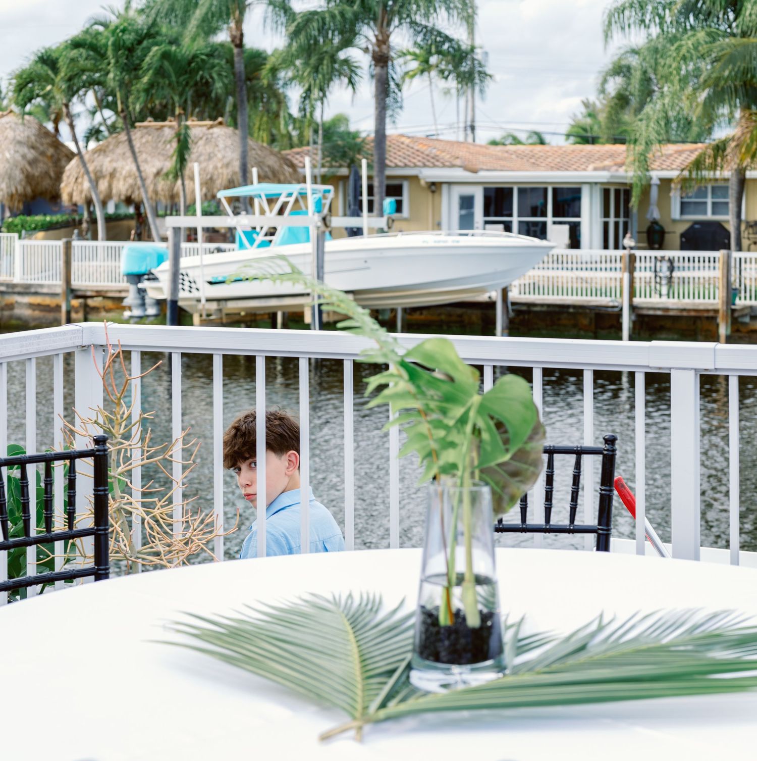 Waterfront venue with palm trees and white railing during a tropical wedding celebration.
