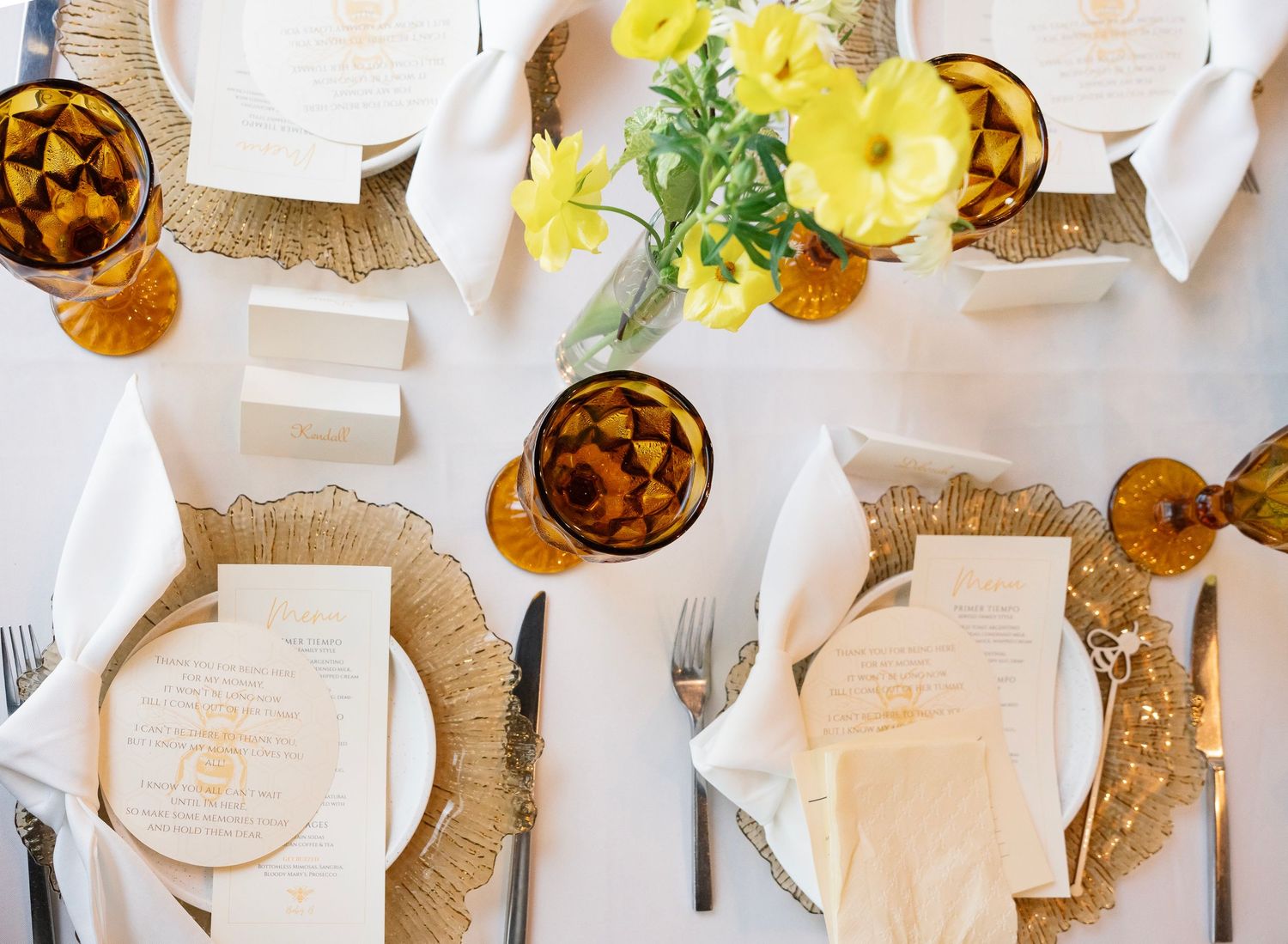 Table setting with white plates, burlap placemats, and yellow floral centerpieces.