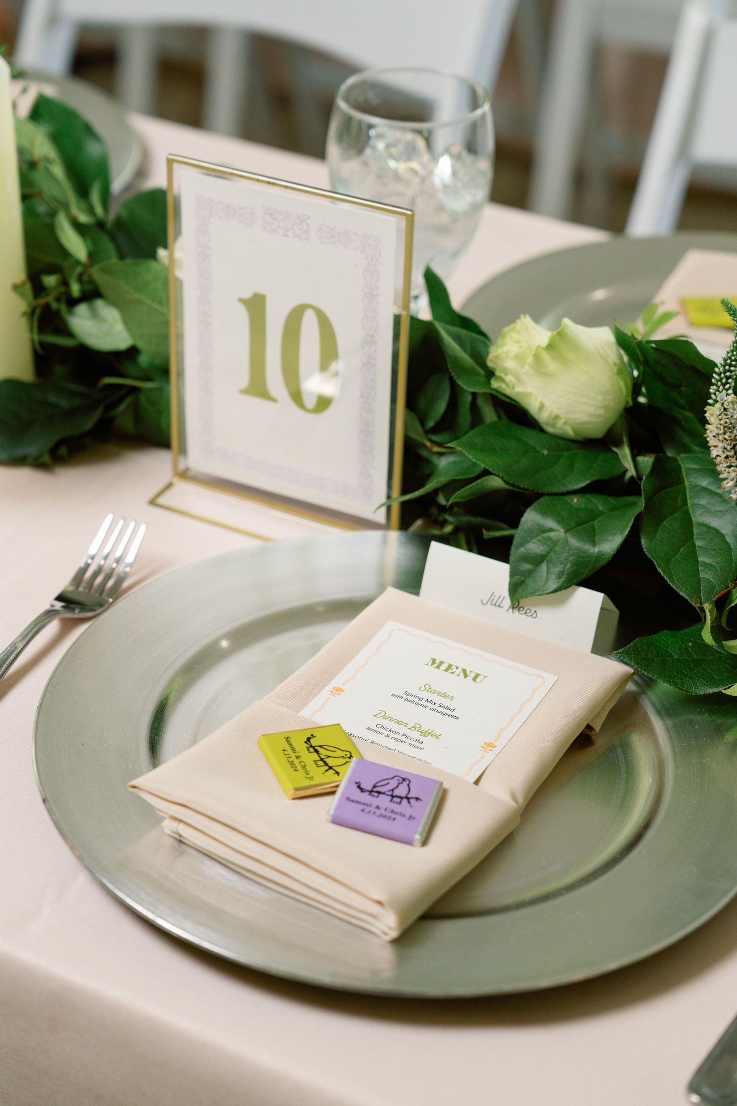 Elegant table setting with menu cards, greenery, and gold table numbers.