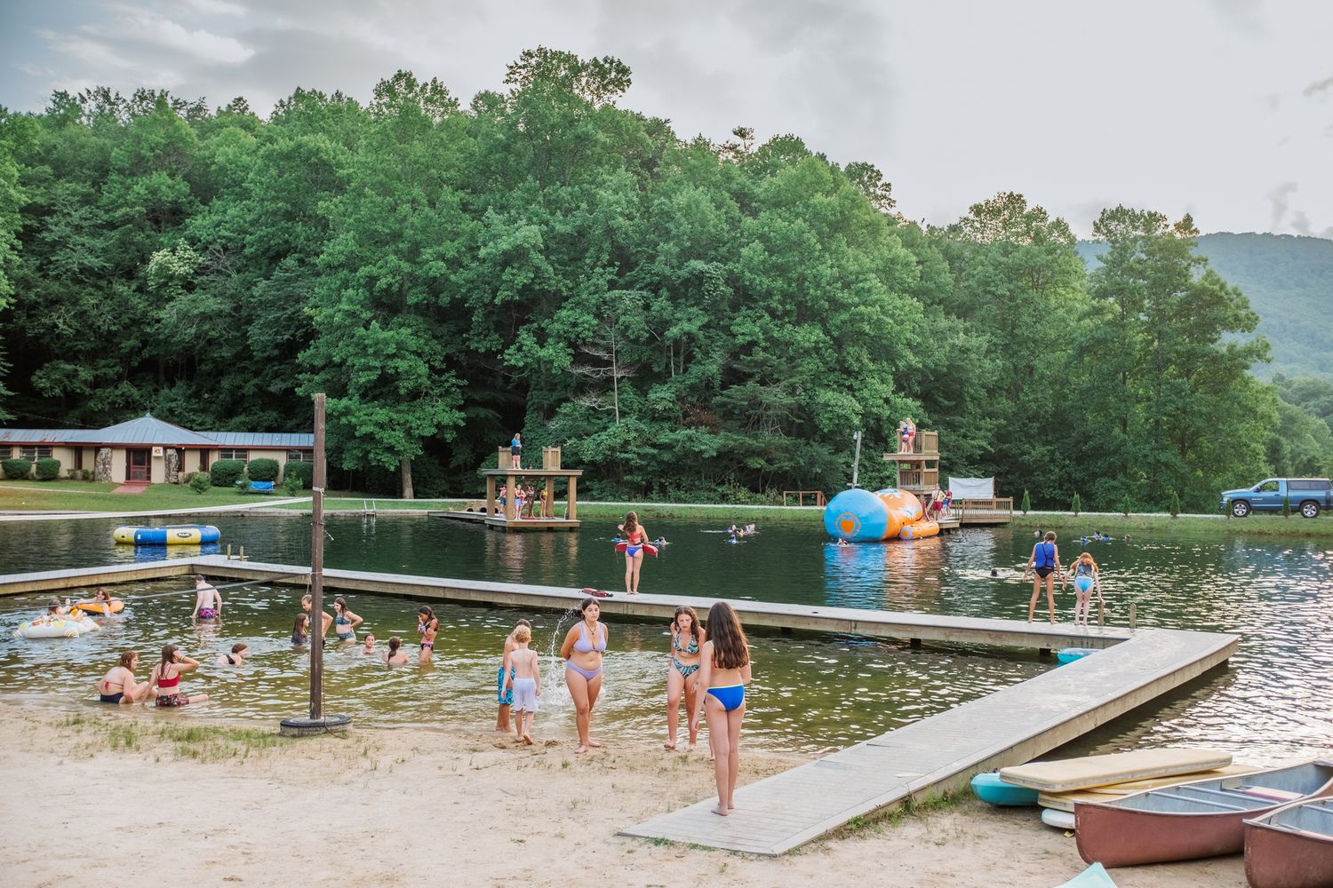 A scenic lakeside beach area with docks and swimming platforms on a summer day.
