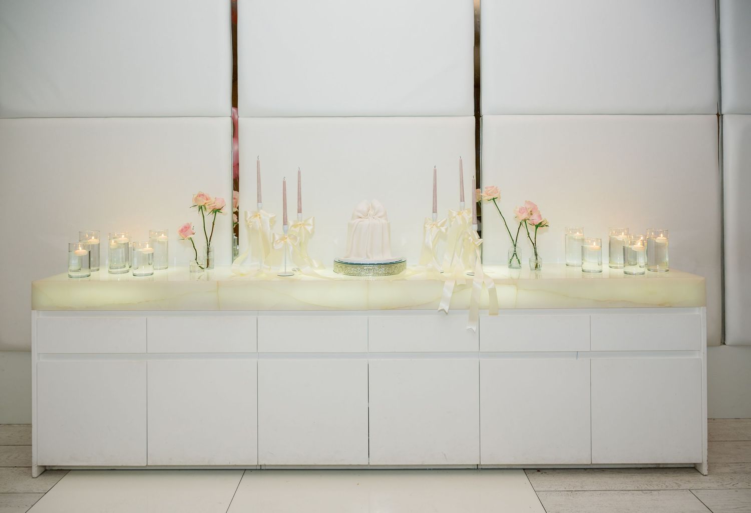 A series of modern minimalist white cabinets with glass display shelves mounted on a wall.