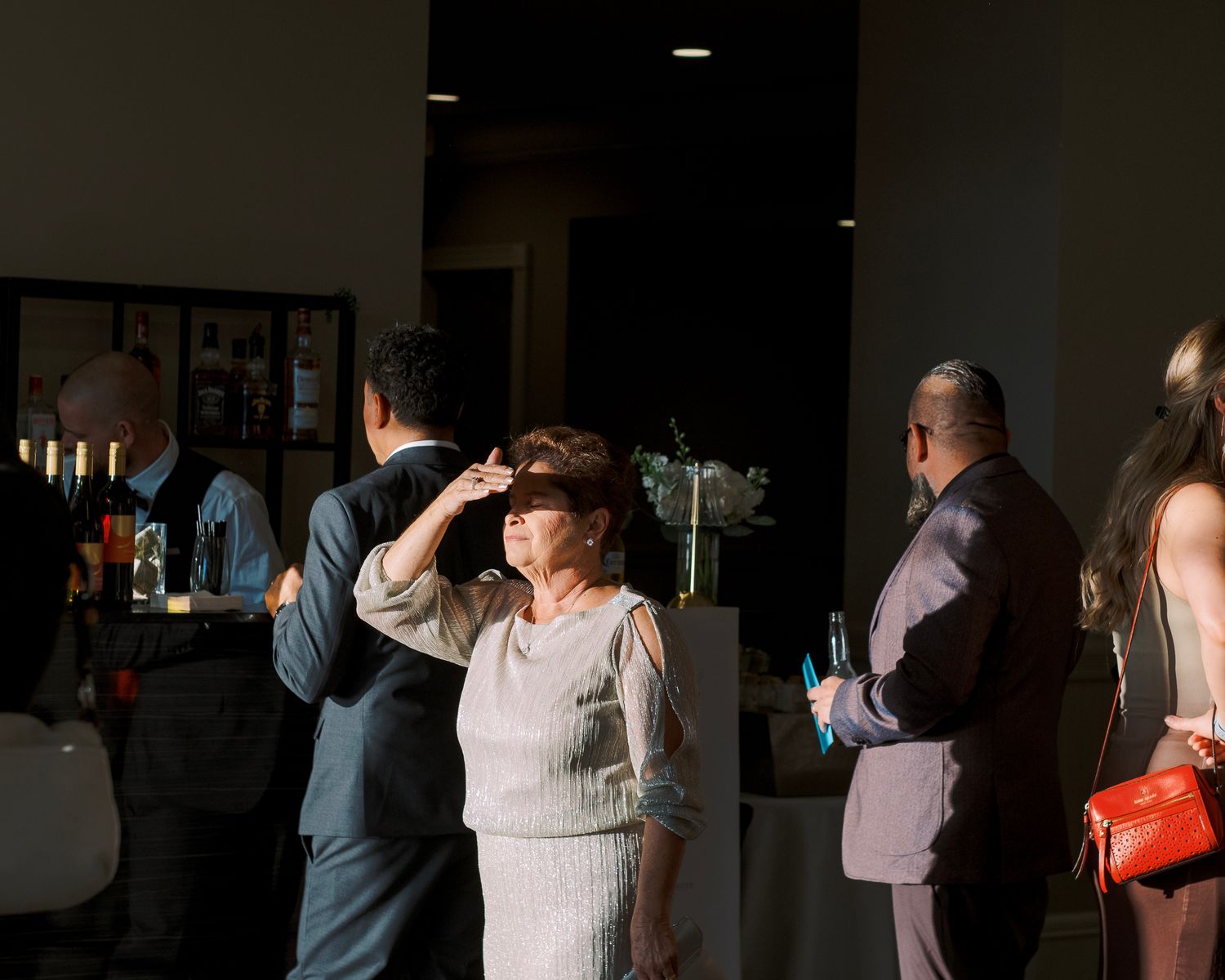 A dark and moody wedding reception dance floor scene with couples dancing in silhouette against dim lighting.