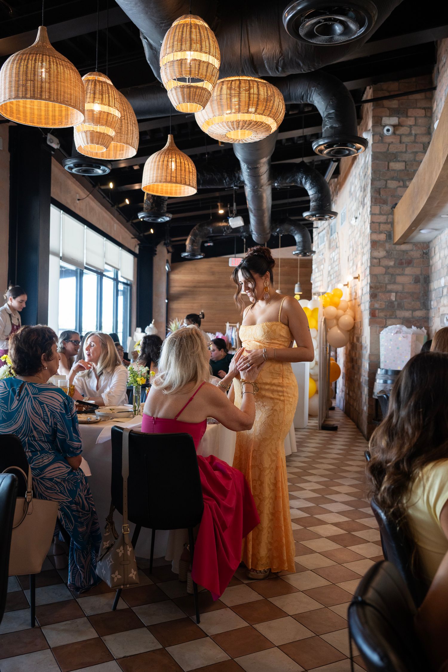 A celebration in a restaurant with bamboo pendant lights and checkered flooring filled with guests.