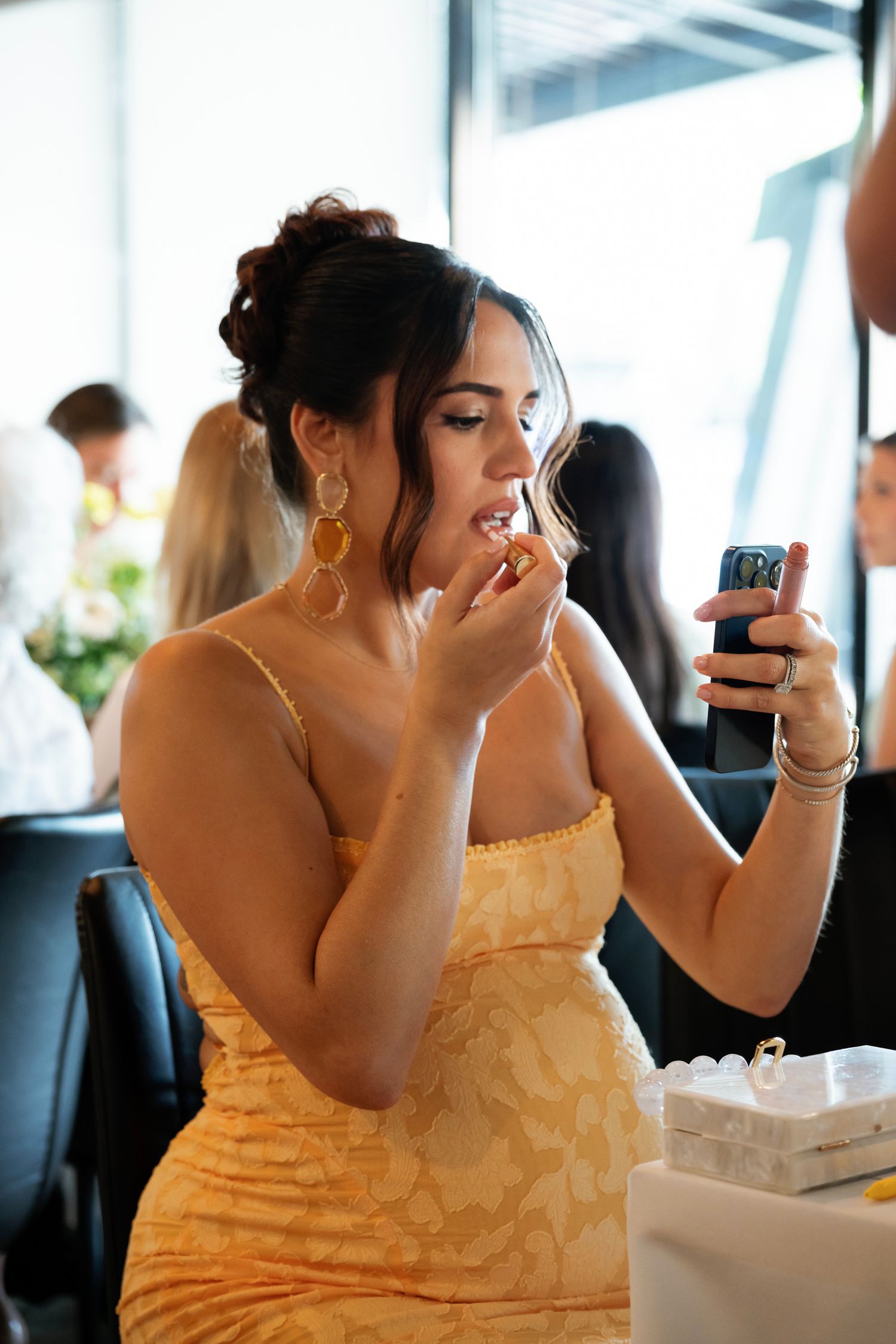 A guest in a yellow dress checks their phone while dining at a restaurant.