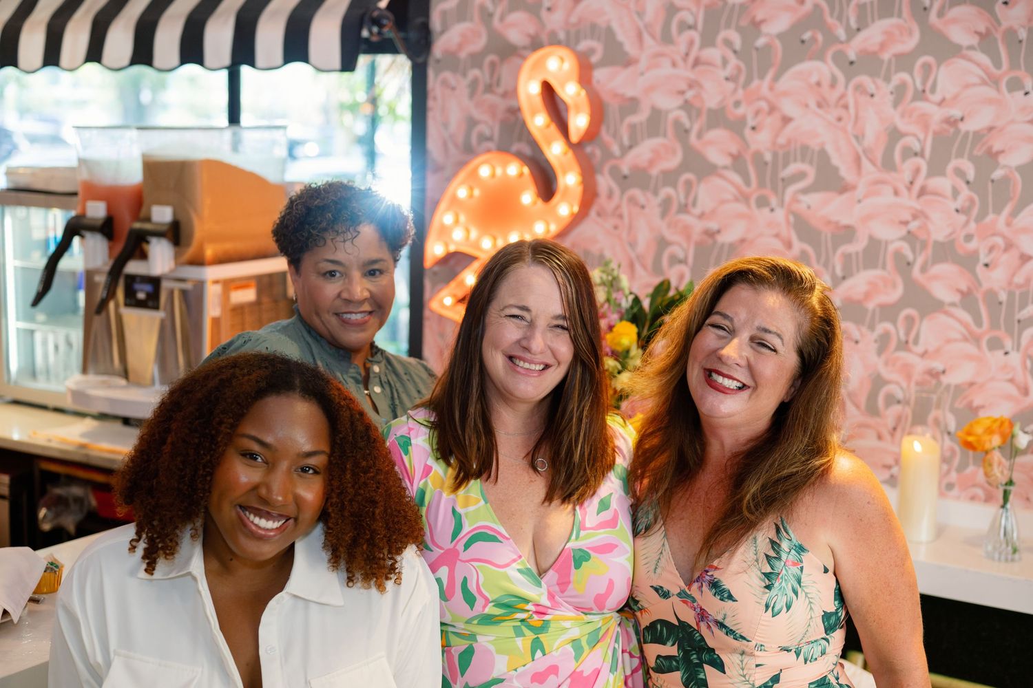 A group enjoying themselves in a stylish restaurant interior with pink floral wallpaper and neon lighting.