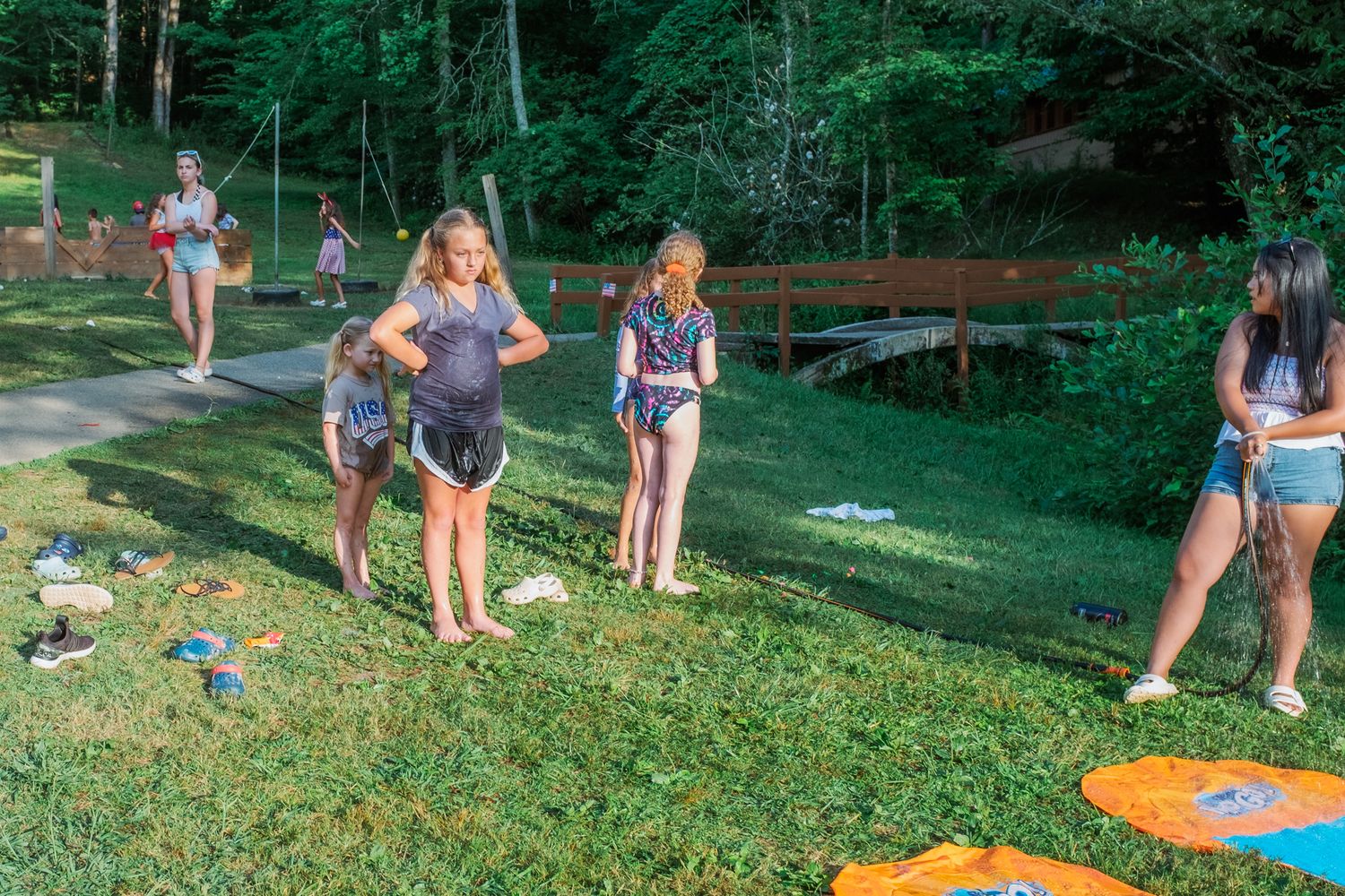 Children playing outdoor games on a grassy hill during a summer event.