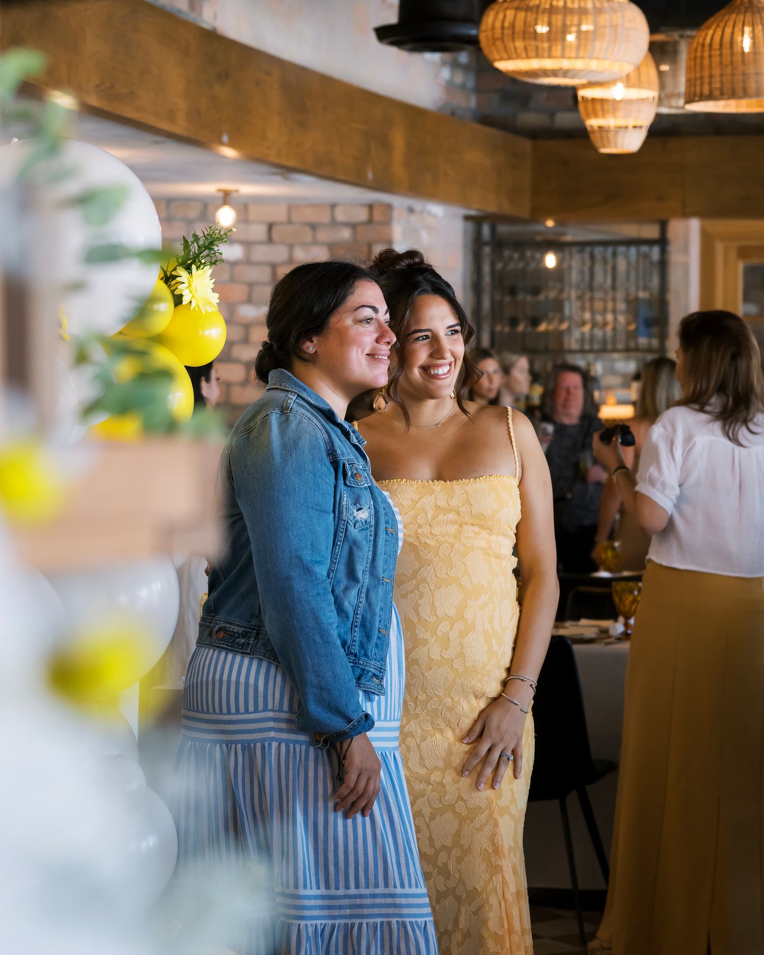 Wedding guests mingle and socialize at an indoor reception with warm lighting and rustic decor.