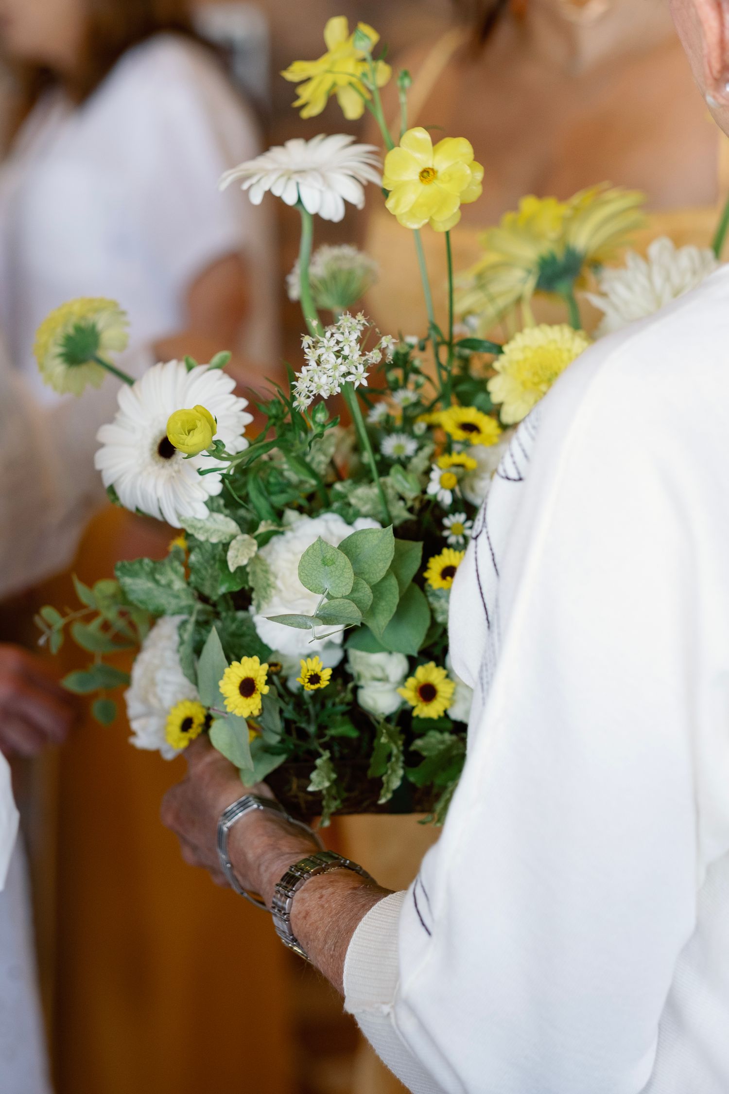 A spring-inspired floral arrangement featuring white daisies and yellow flowers.