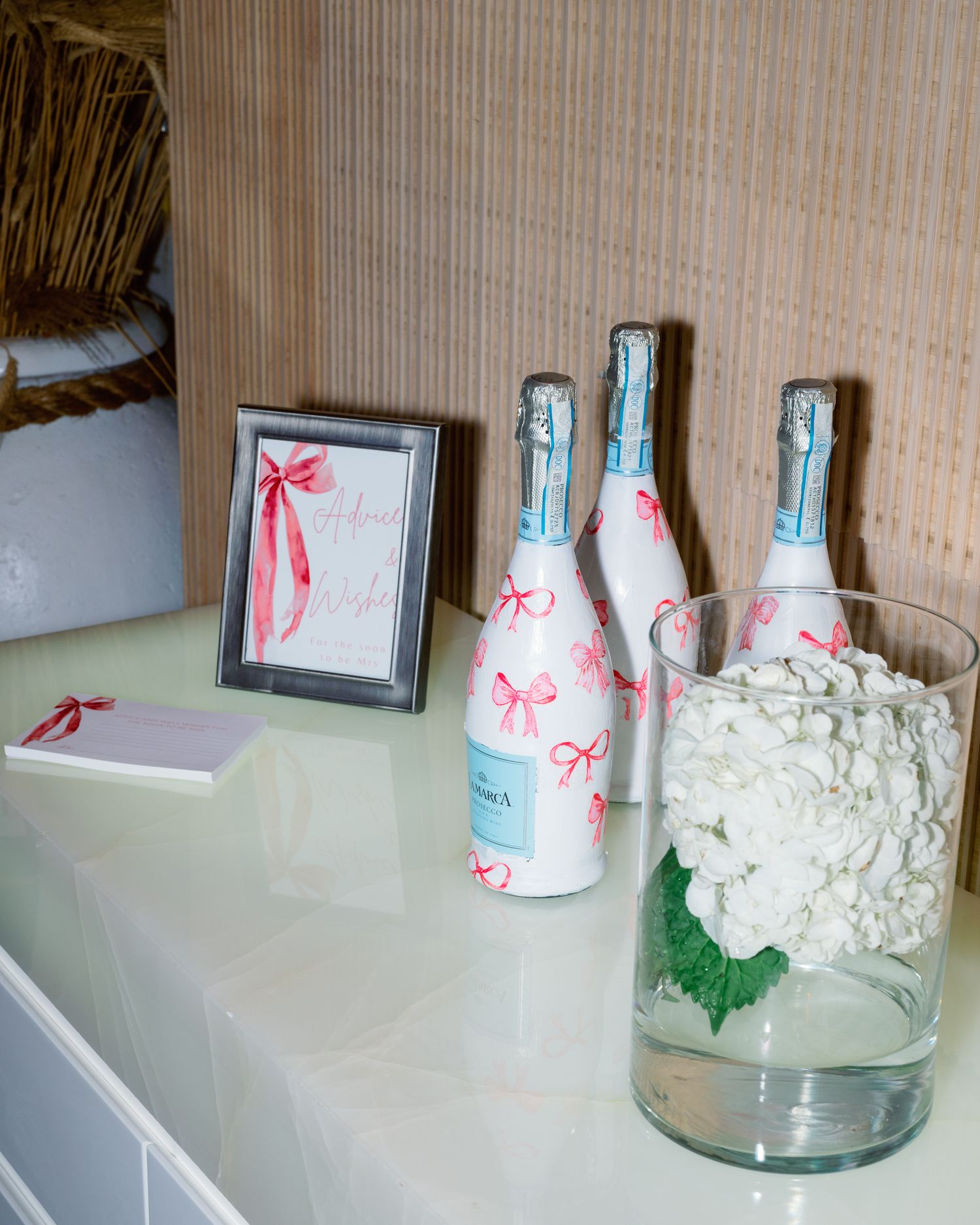 White paper cups with pink ribbons and floral arrangements displayed on white shelving.