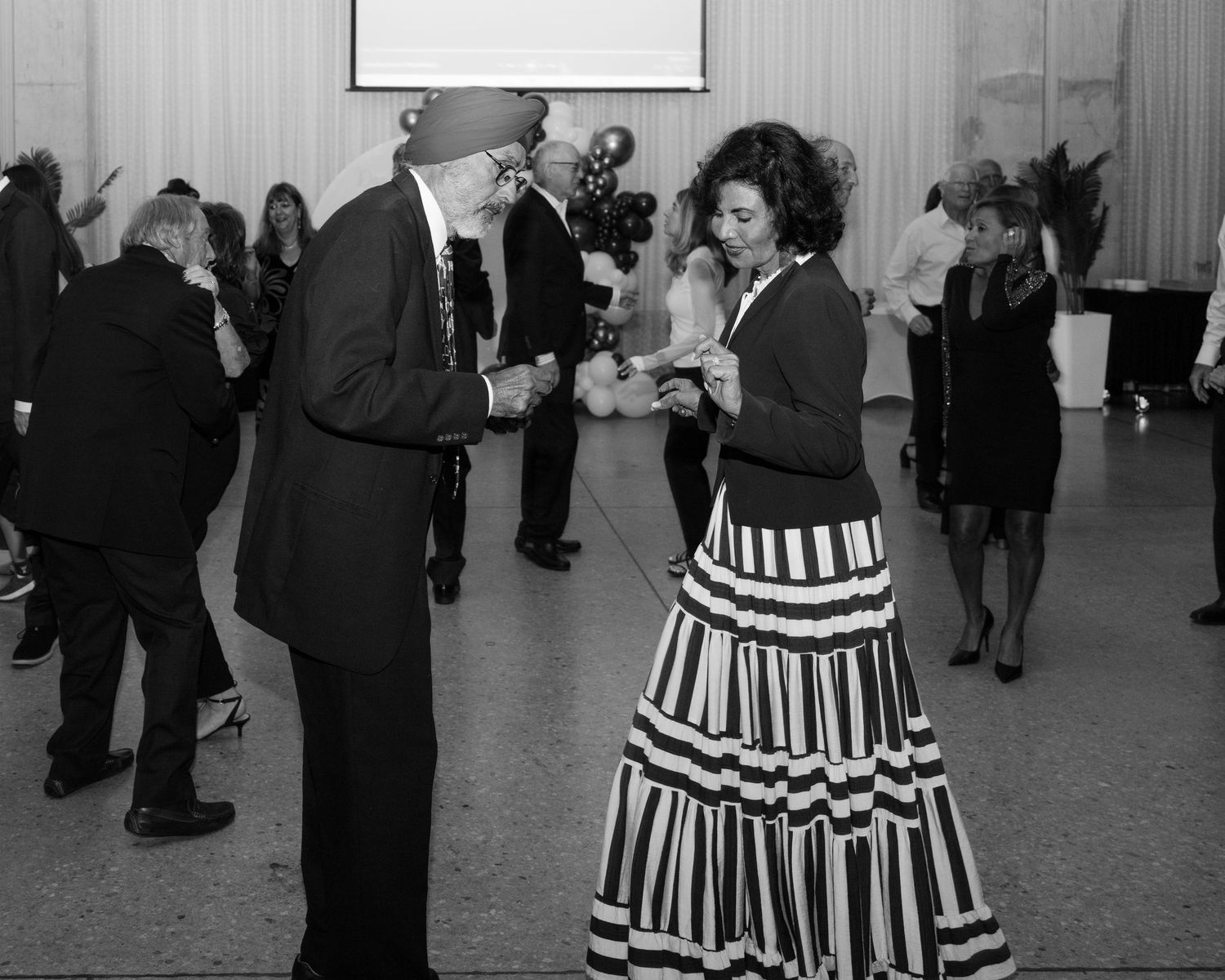 Couples dancing in formal attire at an elegant black and white themed event.