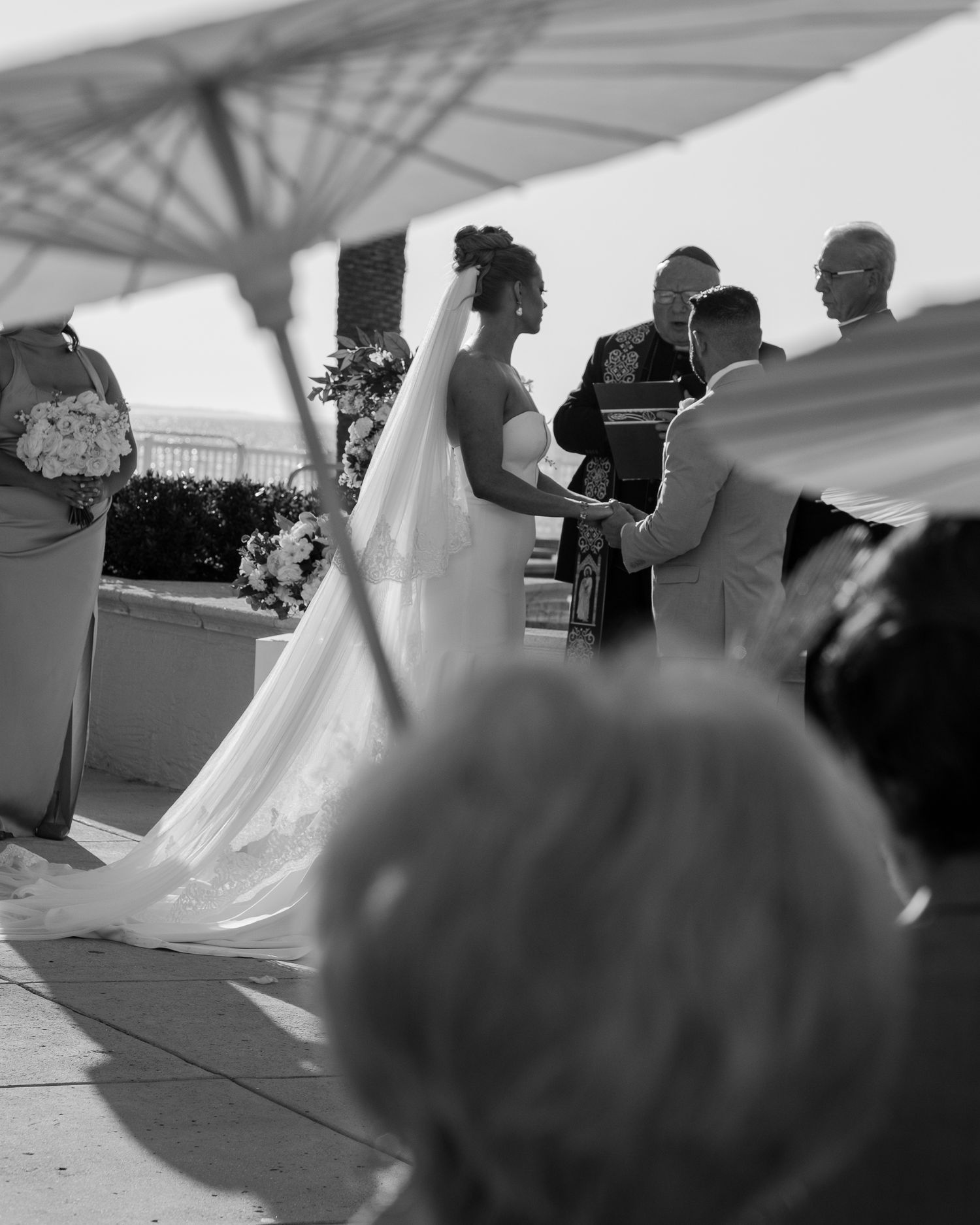 A couple dancing together during their first dance at an outdoor wedding reception under a white tent canopy.