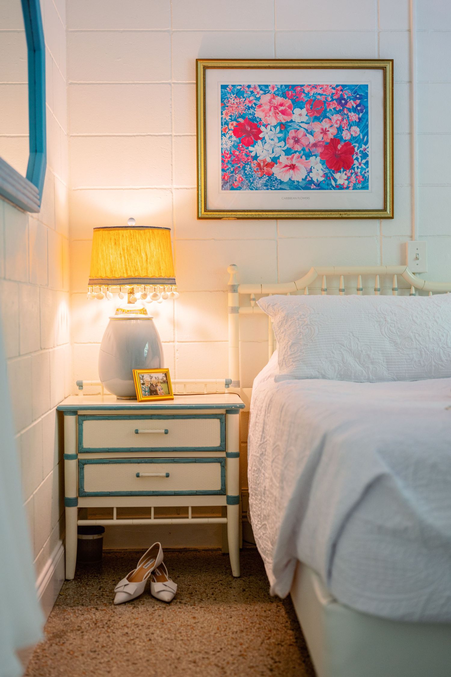 Modern bedroom interior with white bedding, floral artwork, and warm lighting.