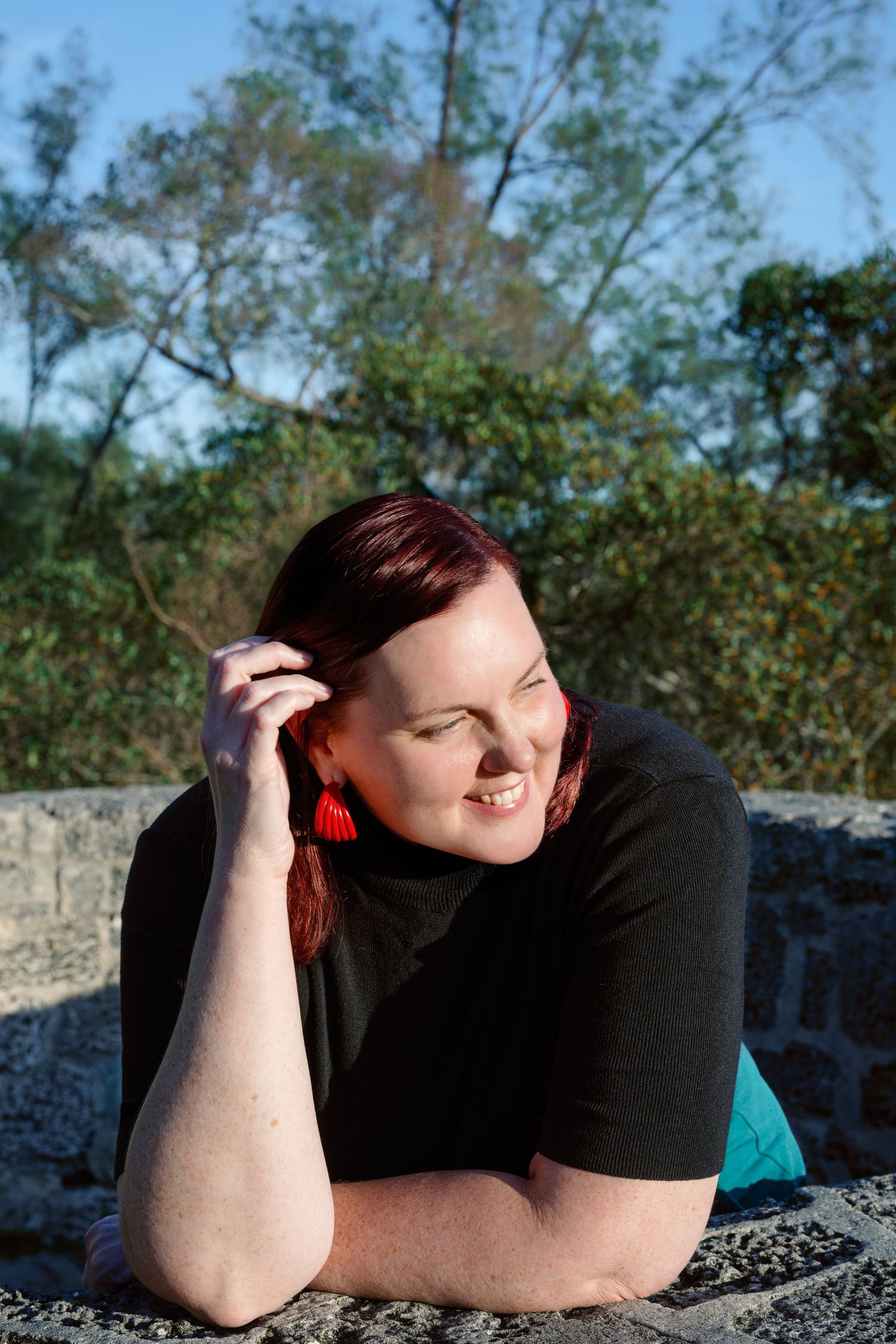 A series of four outdoor portraits showing someone lying on a stone surface in a black shirt with trees in the background.