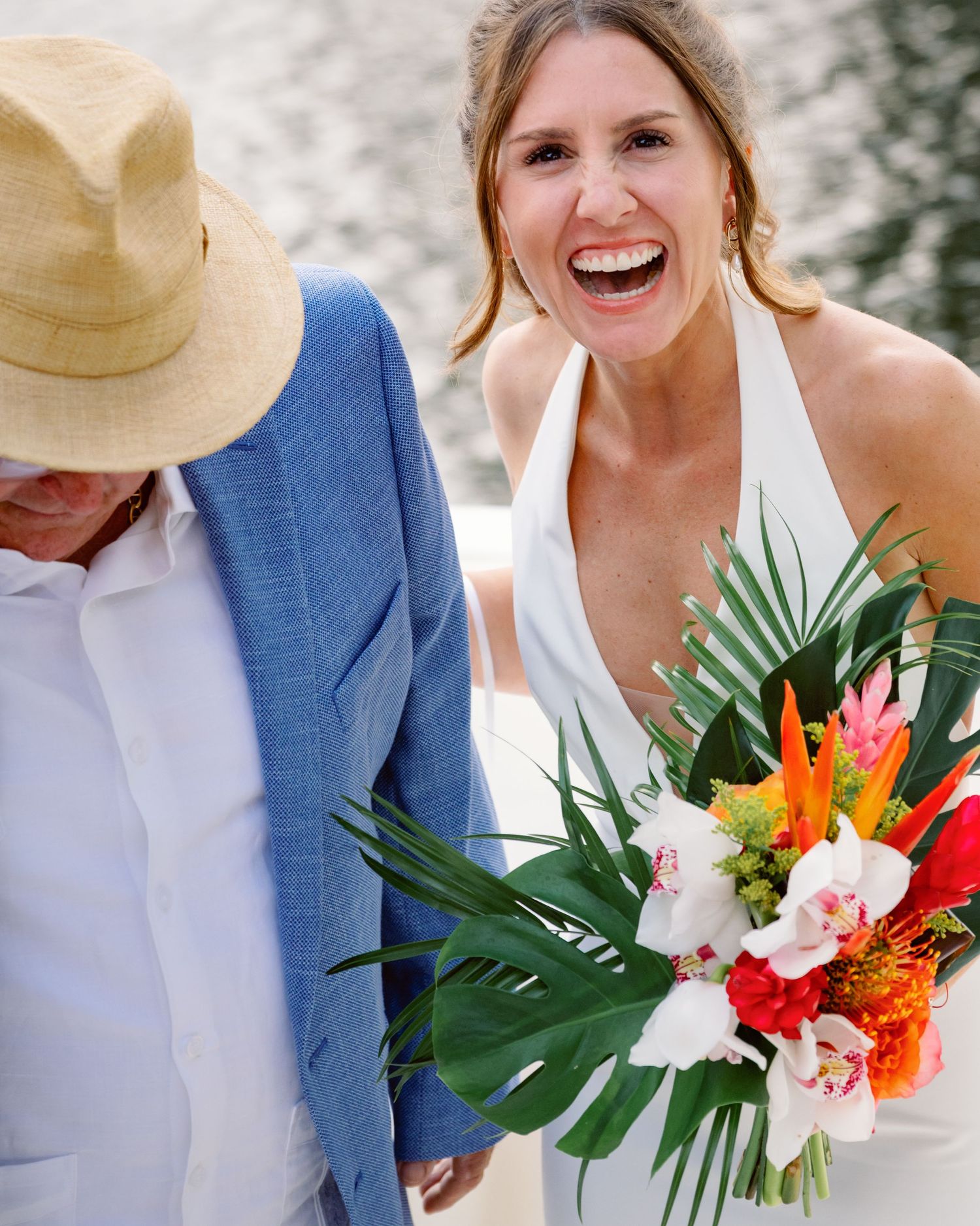 A joyful moment captured with tropical wedding bouquet featuring bright florals and palm leaves.