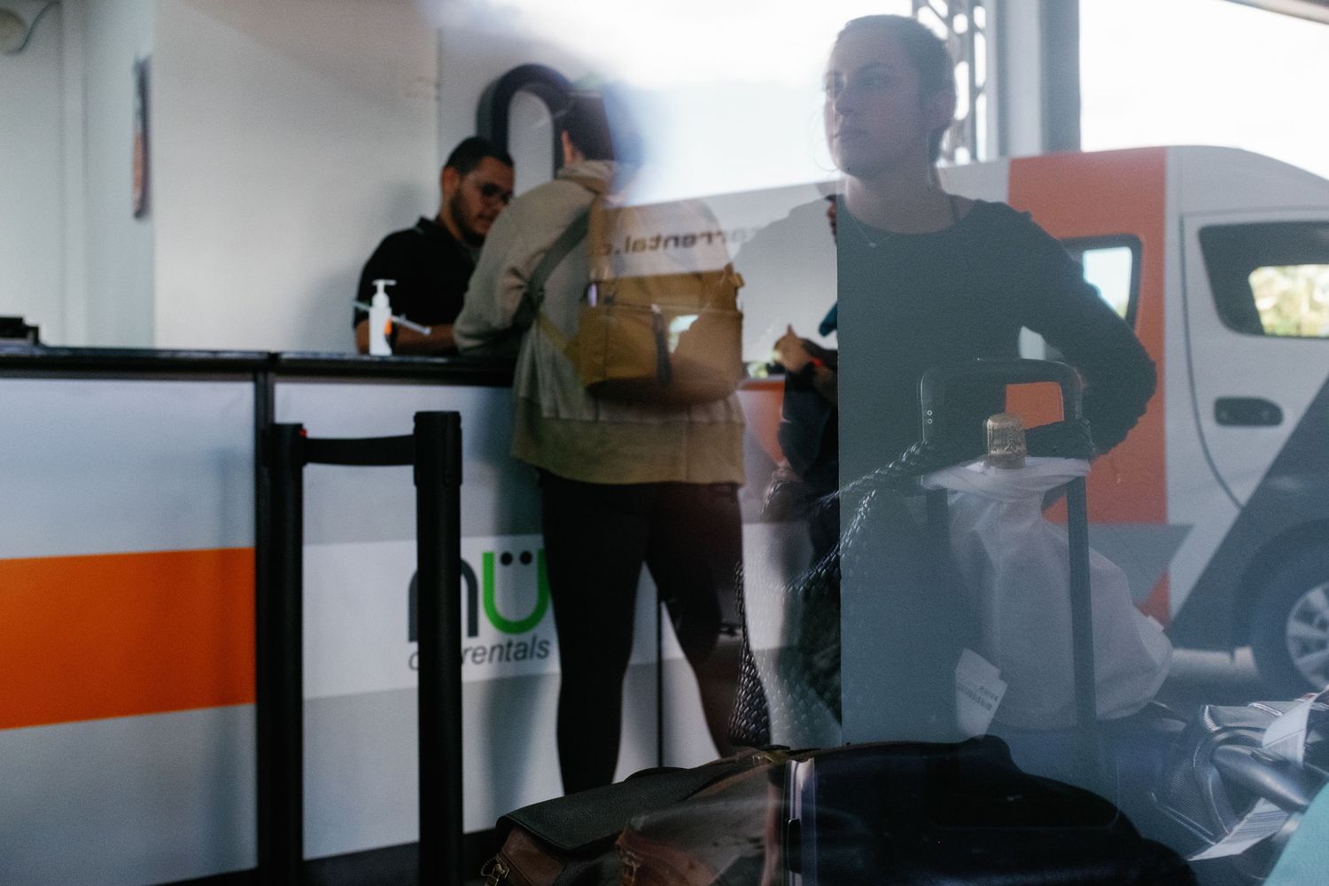 Two people standing inside a modern transit station near an orange and white vehicle.