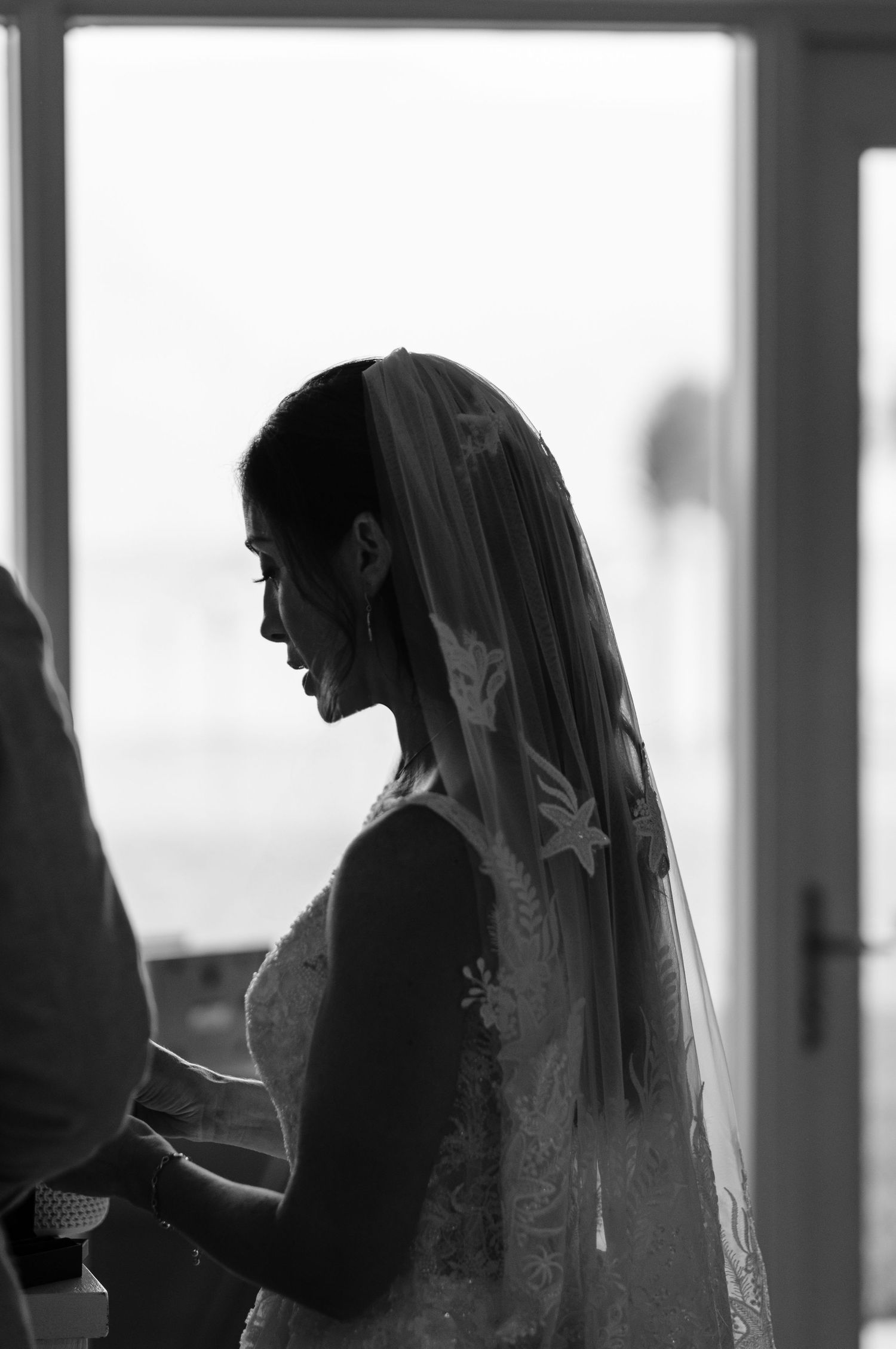Silhouettes of wedding preparations show a bride getting ready against backlit windows.