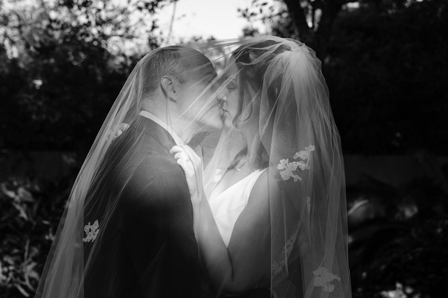 Dramatic black and white wedding photography sequence showing couple embracing in silhouette against natural light.
