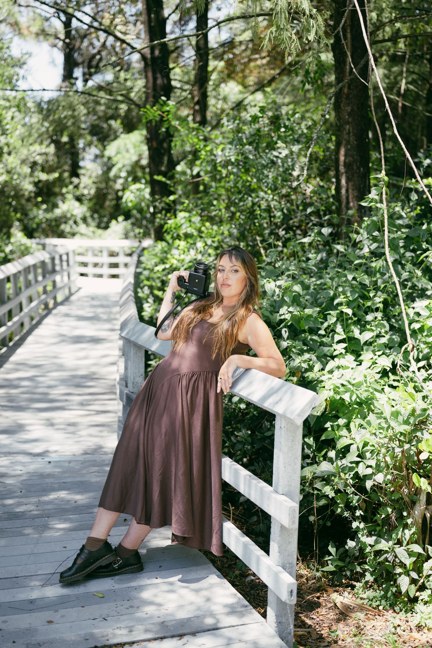 A series of photos showing someone in a brown dress leaning back on a white wooden railing in a lush garden setting.