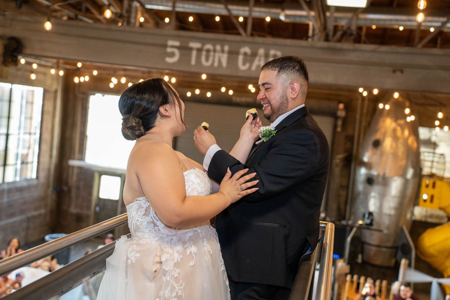 Bride and groom sharing a cake toast moment in front of guests at The Hitching Post in Springville, UT, by N&D Media Production.