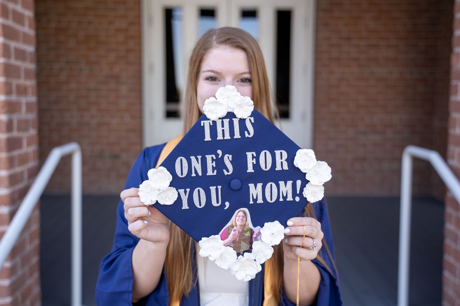 Senior graduation portrait holding a custom cap outside Old Main at the University of Arizona, photographed by N&D Media.