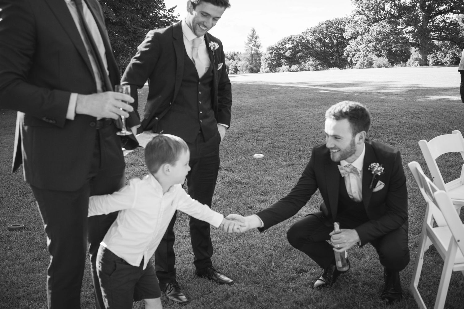 Groom crouches to shake hands with young boy at wedding at Rathsallagh House wedding in Wicklow.
