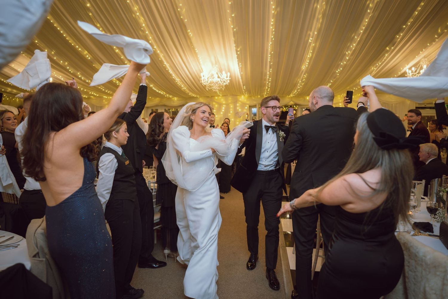 Two young girls in gold and white dresses playing on the floor at a wedding reception.