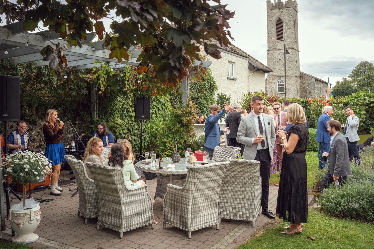 Elegantly dressed wedding guests mingle at outdoor garden reception at garden wedding reception in Co Meath.