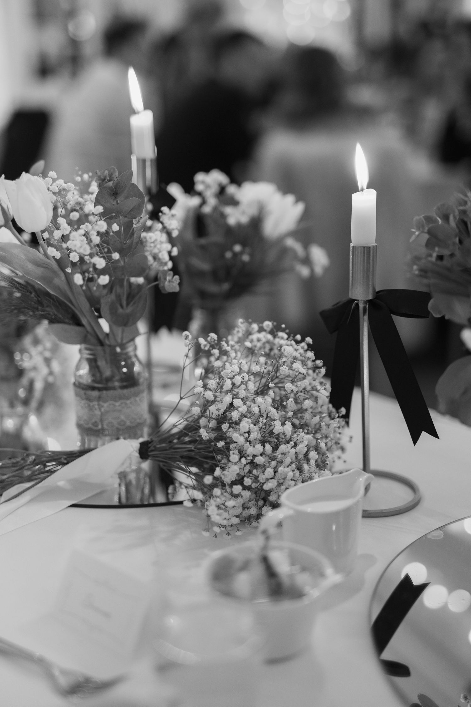 Black and white wedding table centerpiece with lit candles, baby's breath flowers, and elegant floral arrangements.