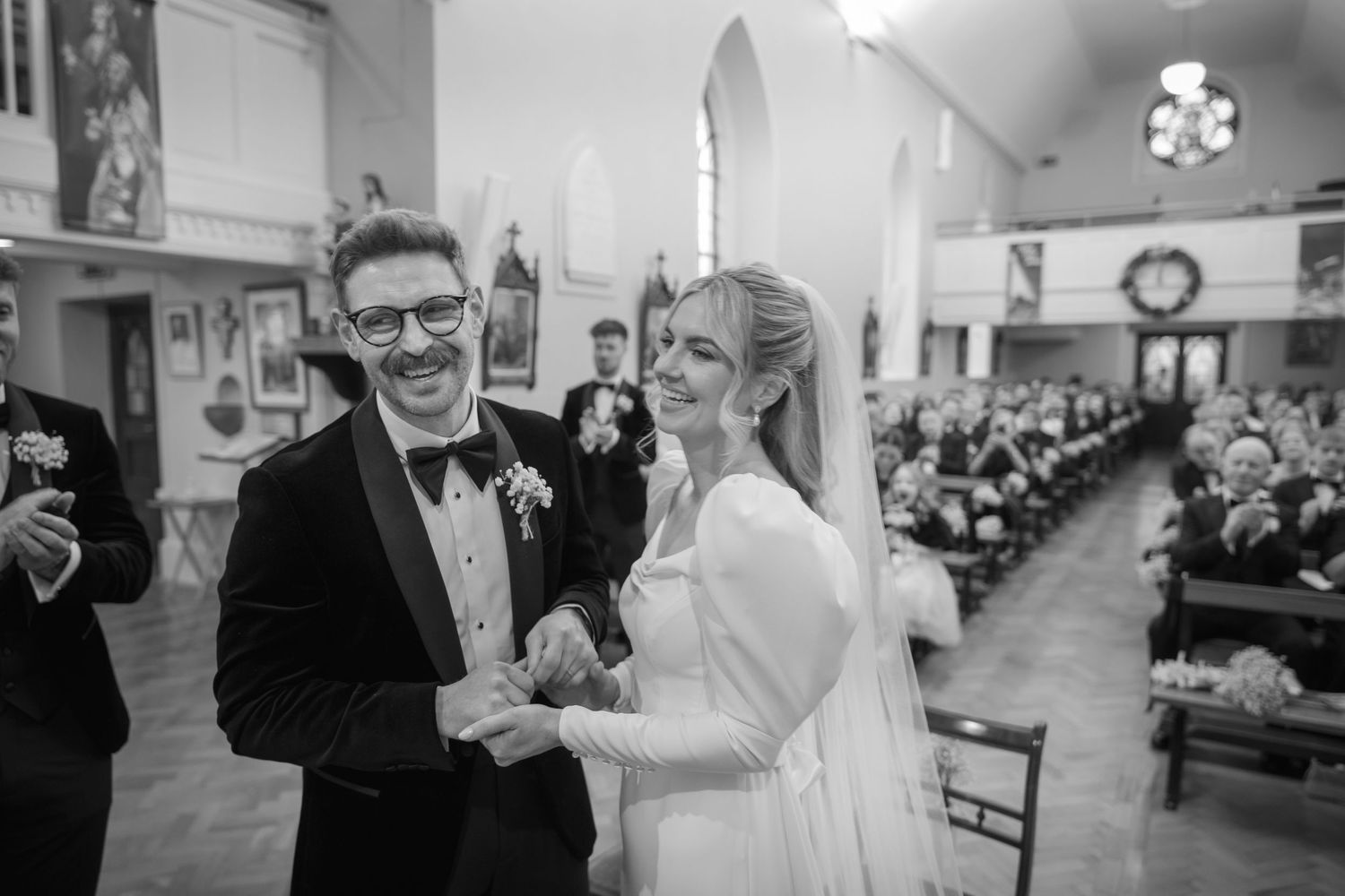 Happy bride and groom exchange rings at church altar, smiling joyfully during wedding ceremony.