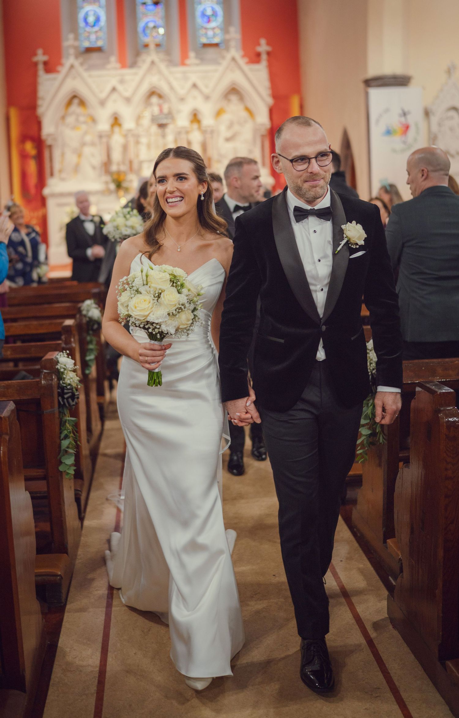 Newlywed couple walking hand in hand down church aisle after wedding ceremony at Mount Juliet wedding Kilkenny.
