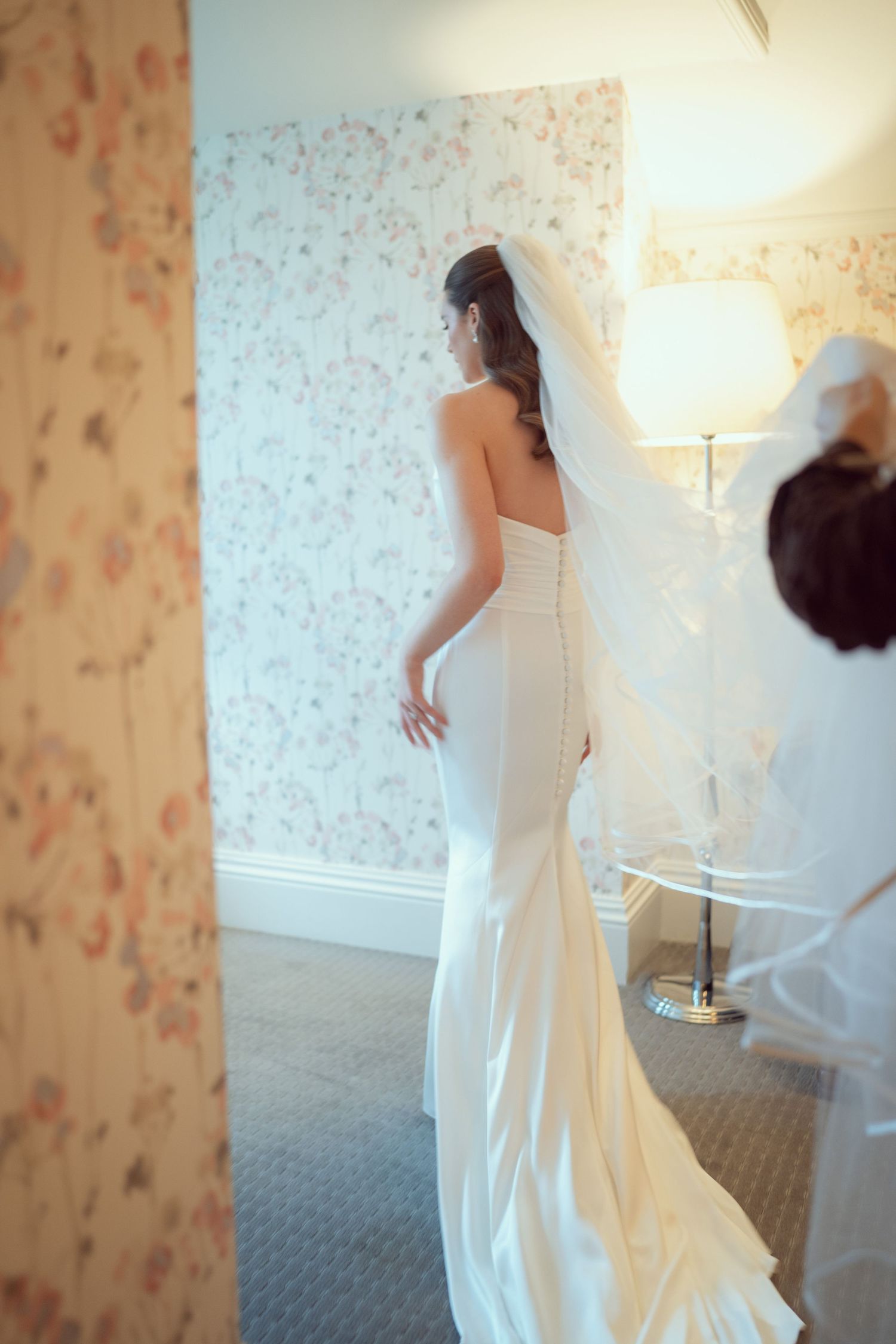 Bride in backless white mermaid gown with long veil in softly lit room at Mount Juliet wedding in Kilkenny.