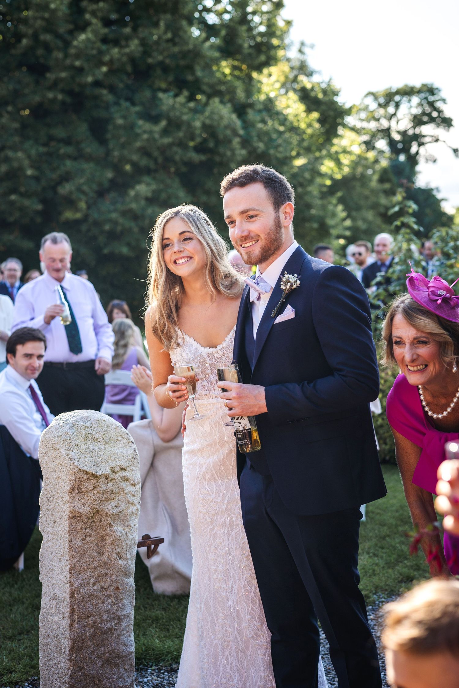 Smiling bride and groom holding champagne glasses at outdoor wedding reception at Rathsallagh House wedding in Wicklow.