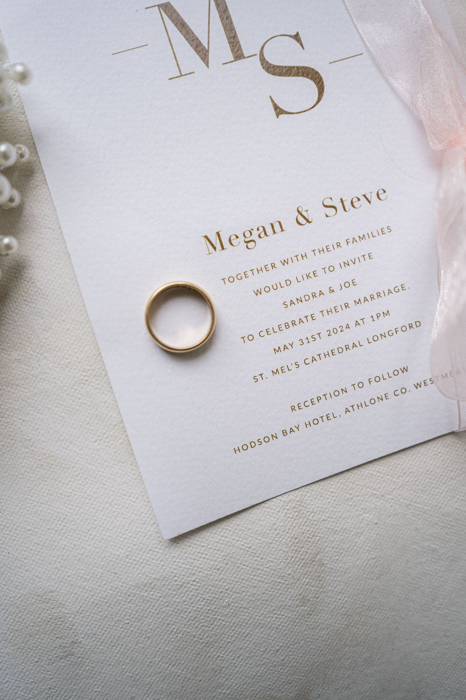 Elegant wedding invitation for Megan and Steve with gold ring on white card, May 31st 2026.