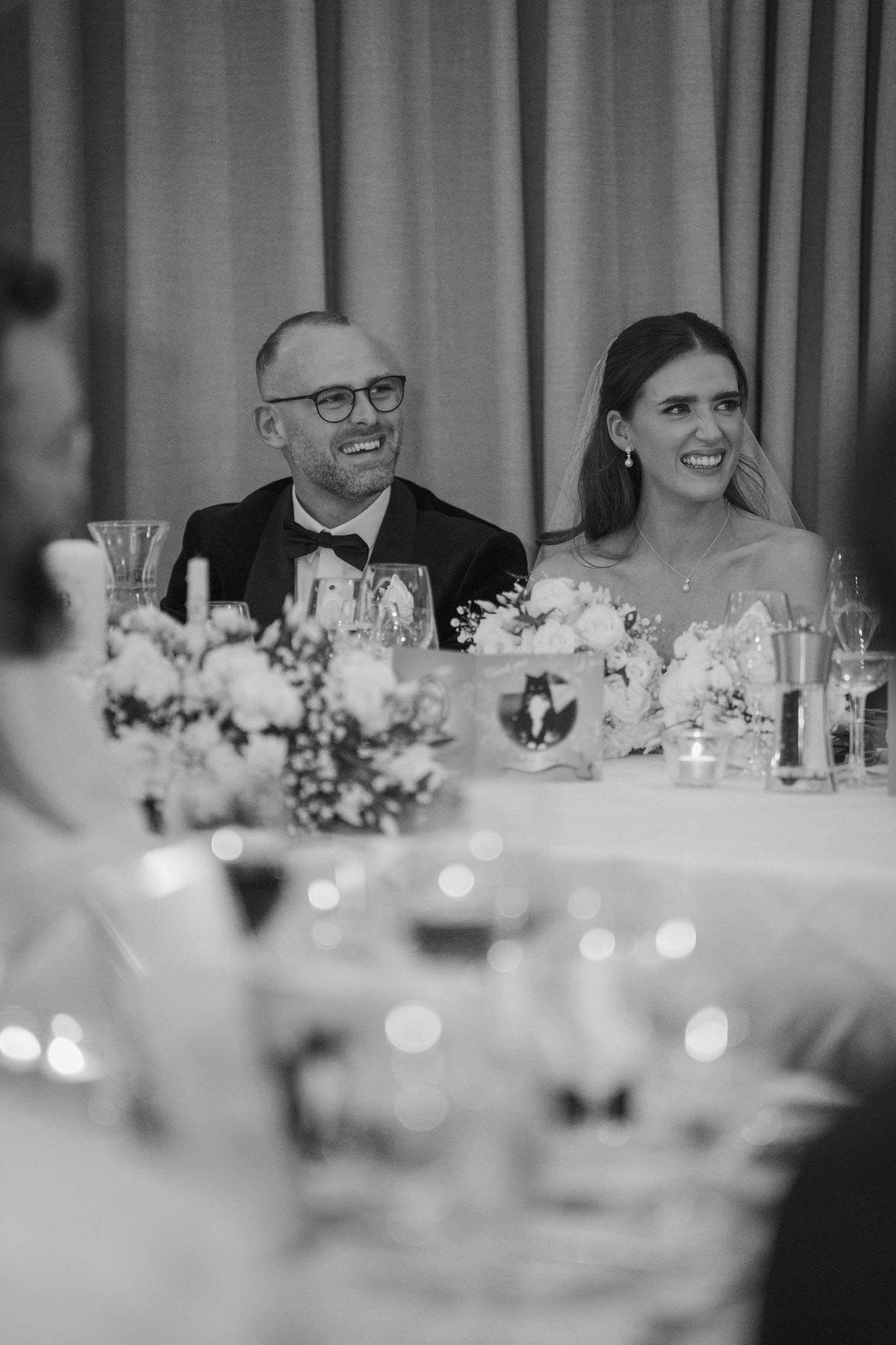 Bride and groom smiling joyfully at their wedding reception dinner table with floral centerpieces at Mount Juliet wedding in Kilkenny.