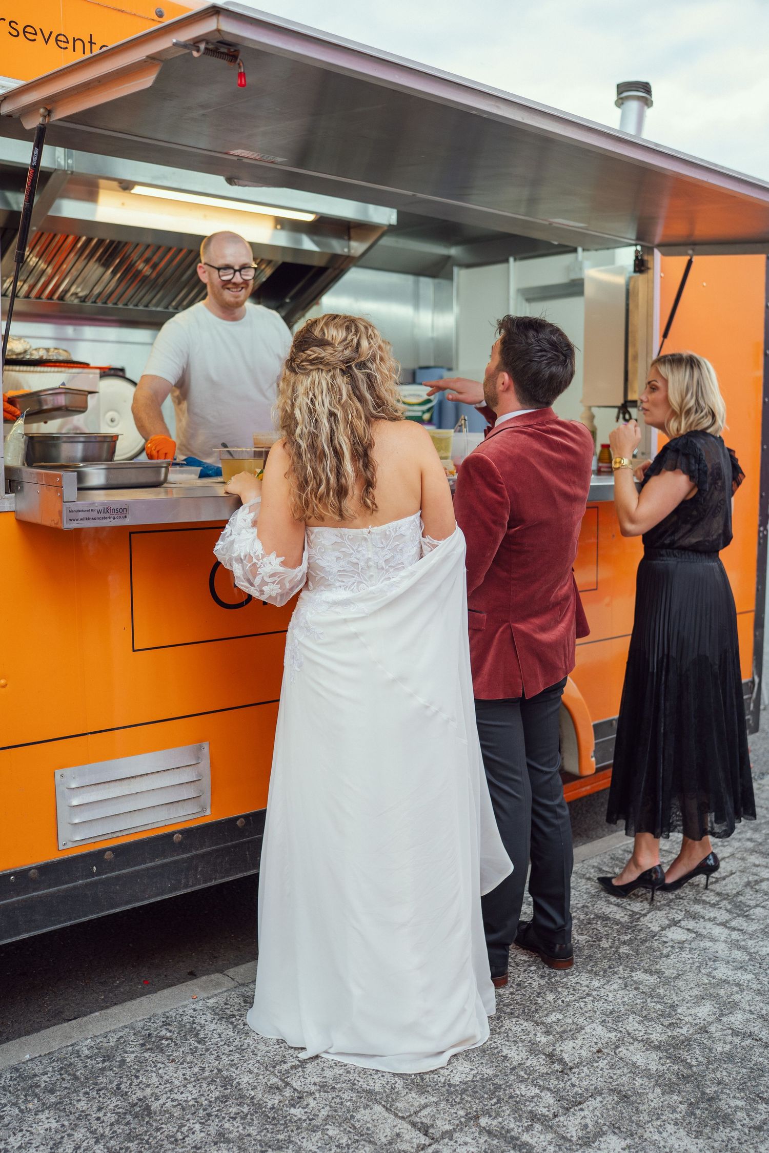A bride and groom ordering food from food truck with guests at their wedding reception at outdoor garden wedding reception in Co Meath.