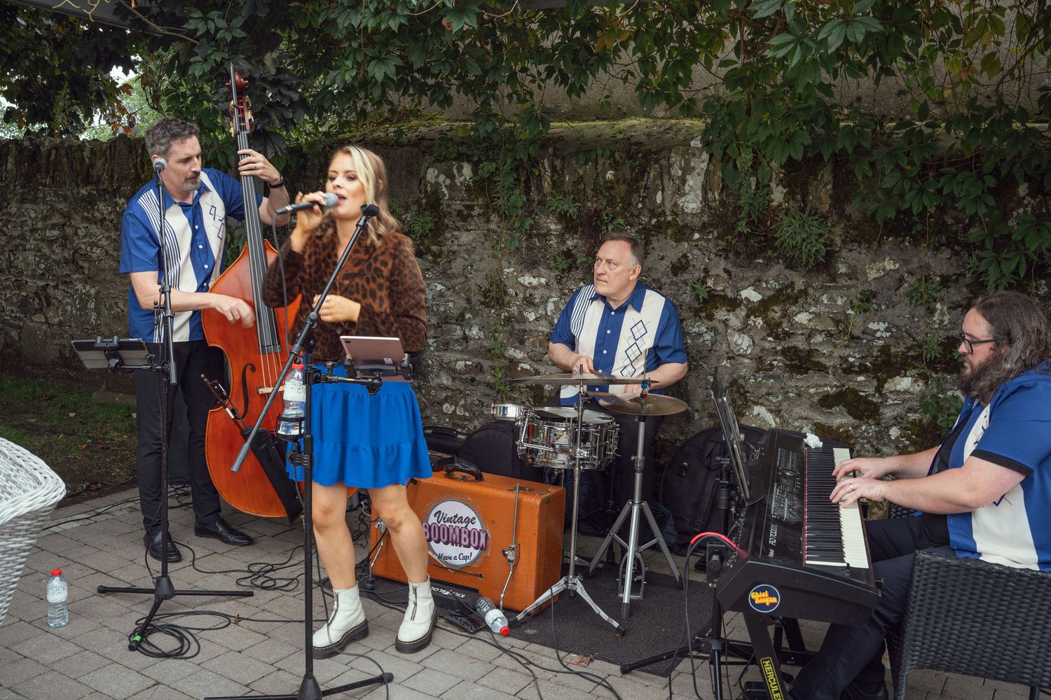 Live retro band performing outdoors at wedding with upright bass, and female vocalist at outdoor garden wedding reception in Co Meath.
