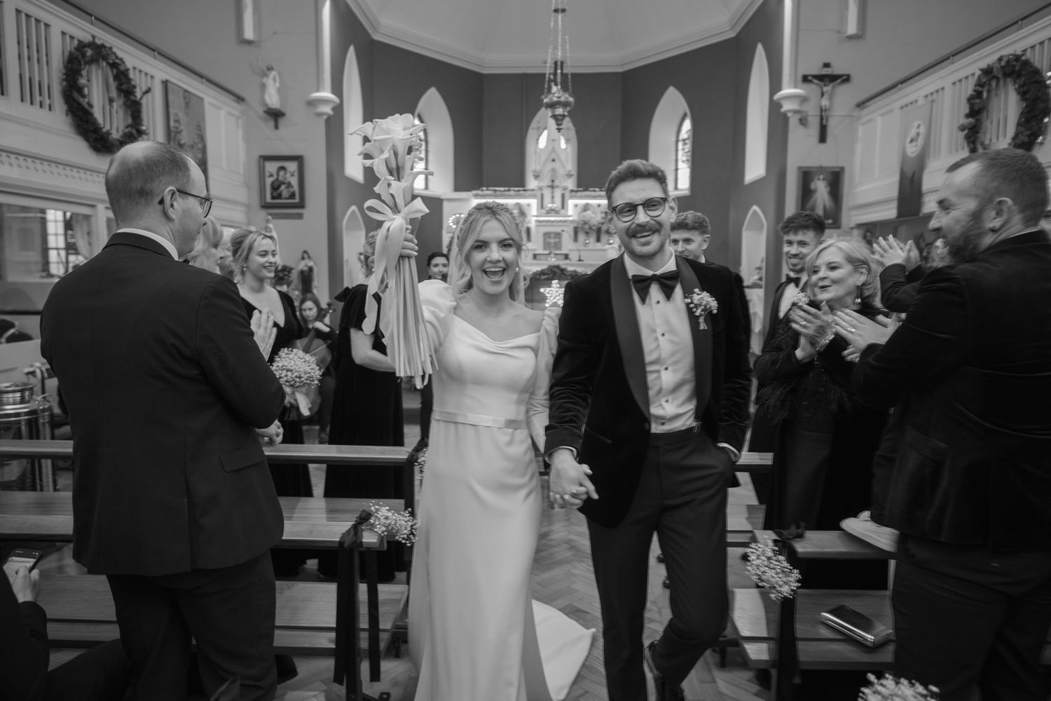 Newlyweds celebrating joyfully while walking back down church aisle after wedding ceremony.