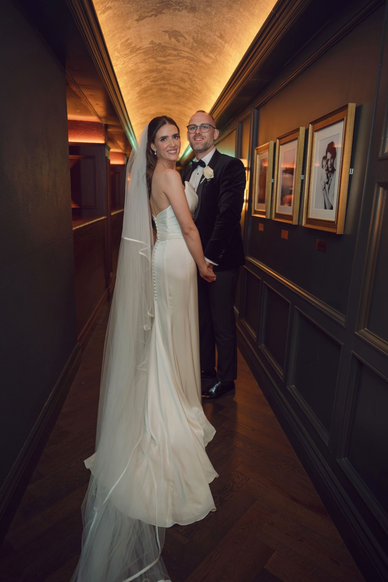 Bride in white gown with veil and groom in tuxedo holding hands in an ornate hallway at the Manor House Mount Juliet wedding Kilkenny.