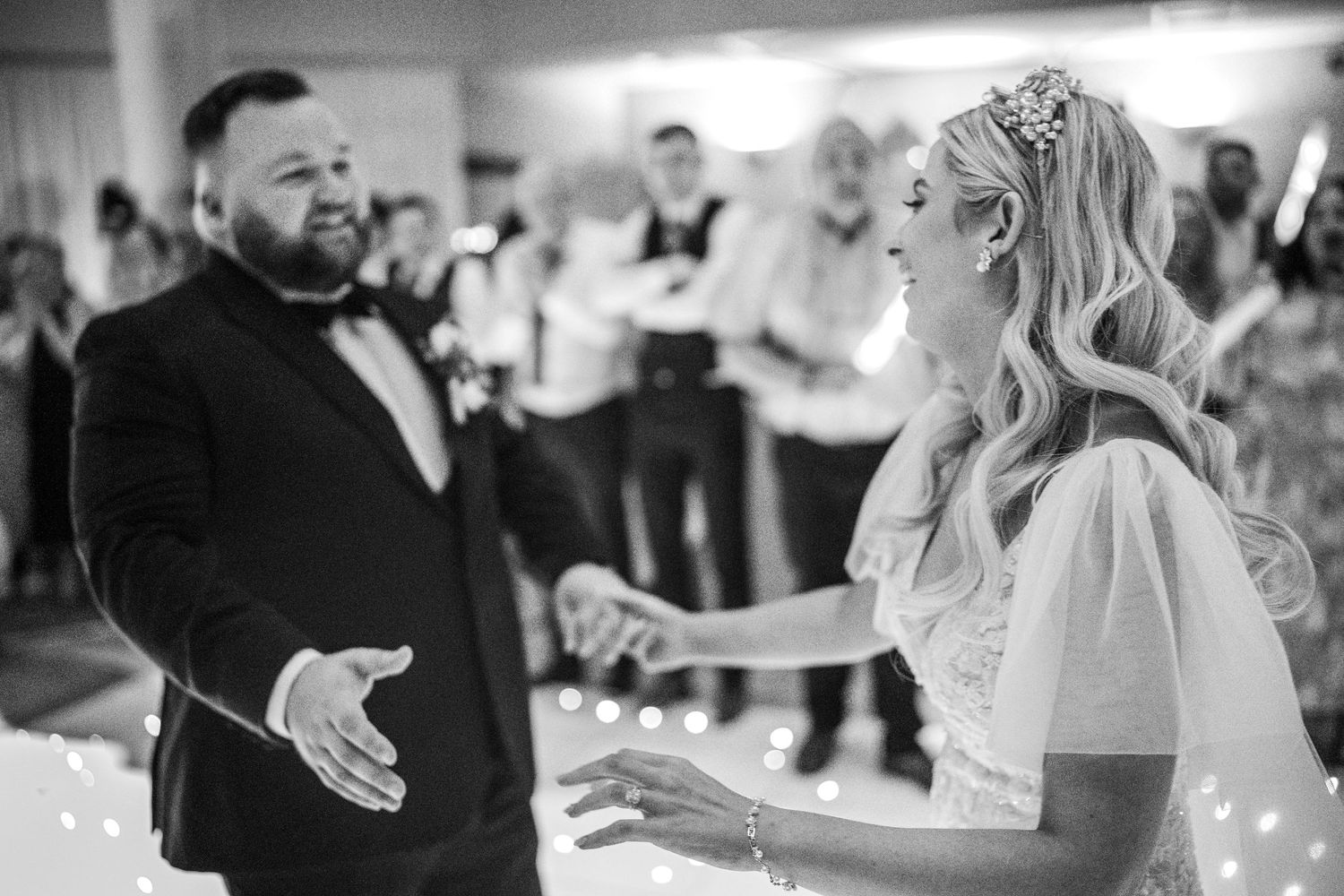 Bride and groom share a joyful first dance at their wedding reception in black and white photography.