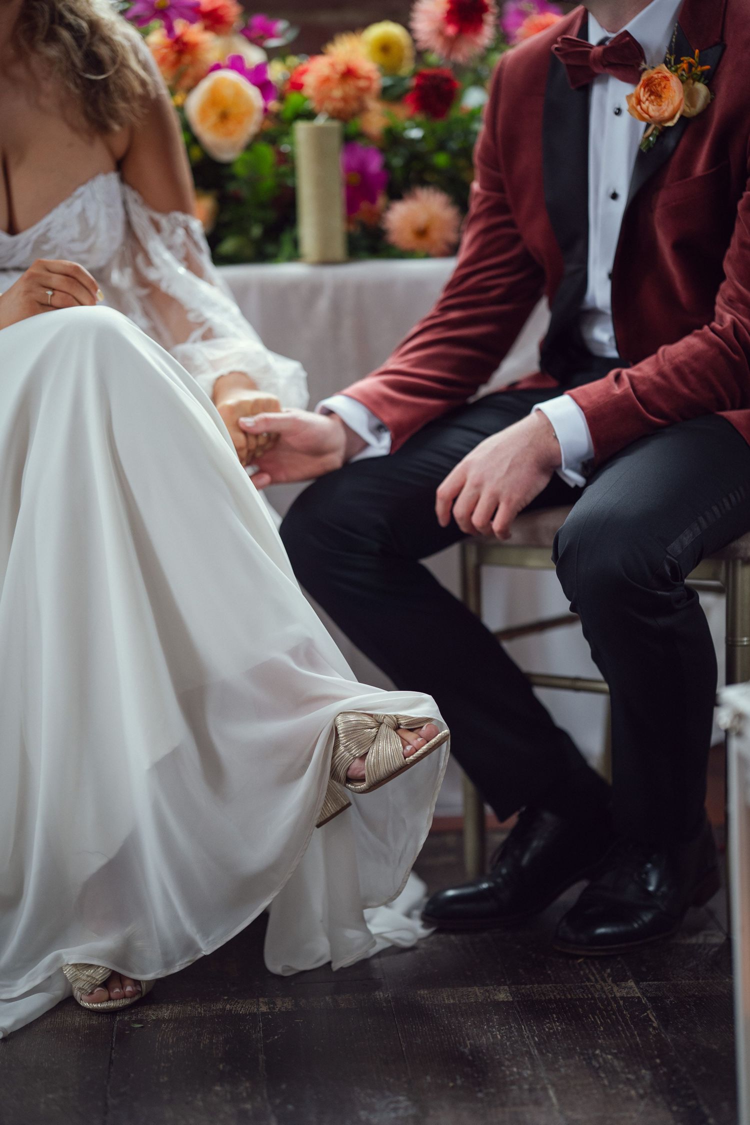 Bride and groom hold hands while seated at wedding ceremony altar at red chapel Kells in Co Meath.