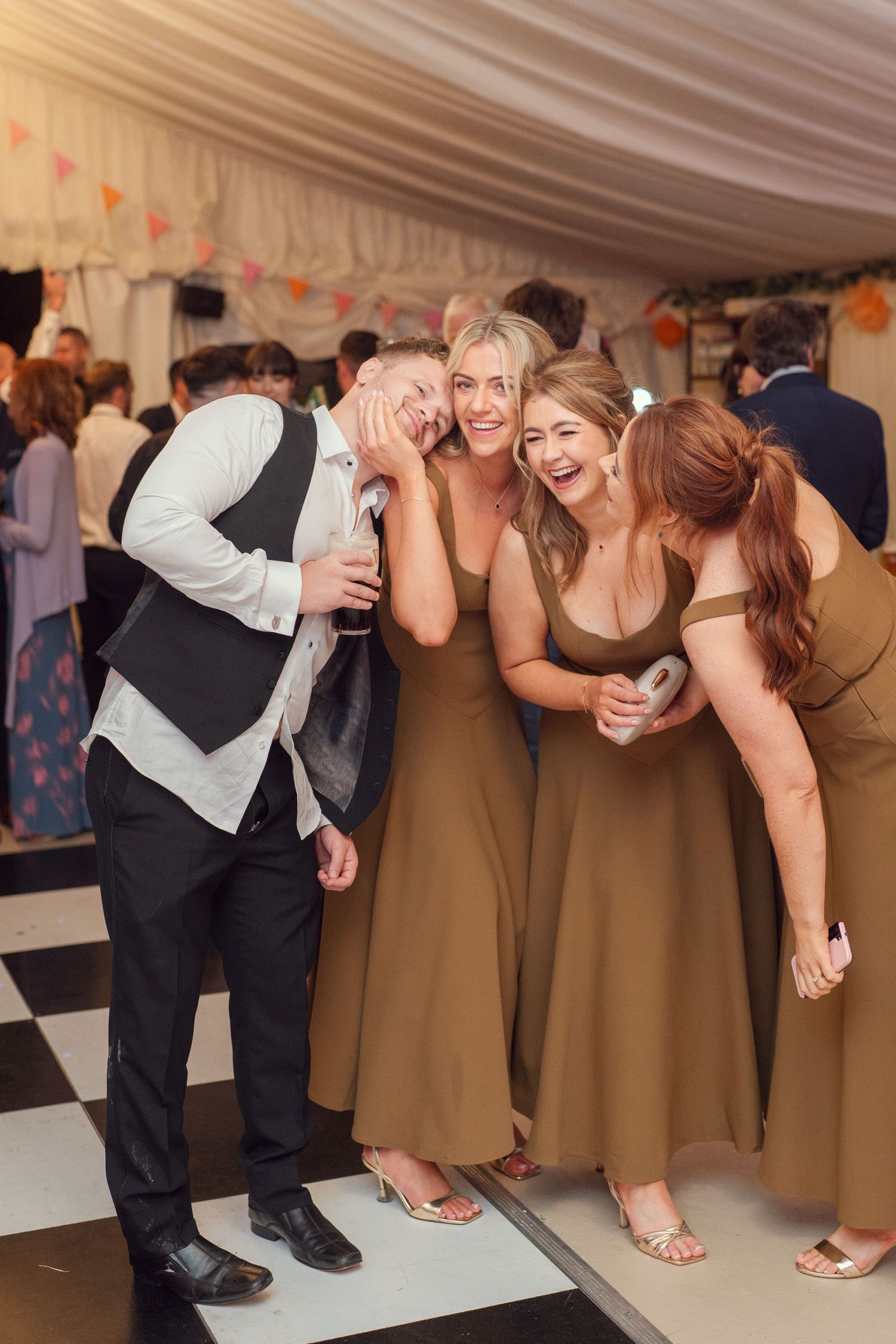 Bridesmaids in gold dresses laughing with a groomsman at outdoor garden wedding reception in Co Meath.