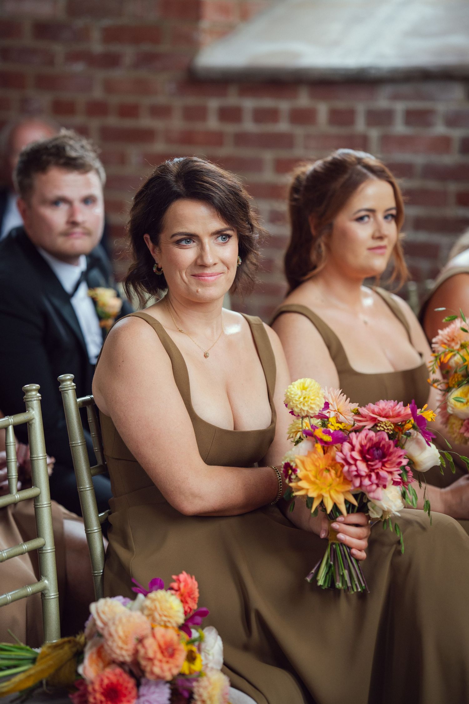 Bridesmaids in olive green dresses holding colorful floral bouquets during wedding ceremony at red chapel Kells in Co Meath.