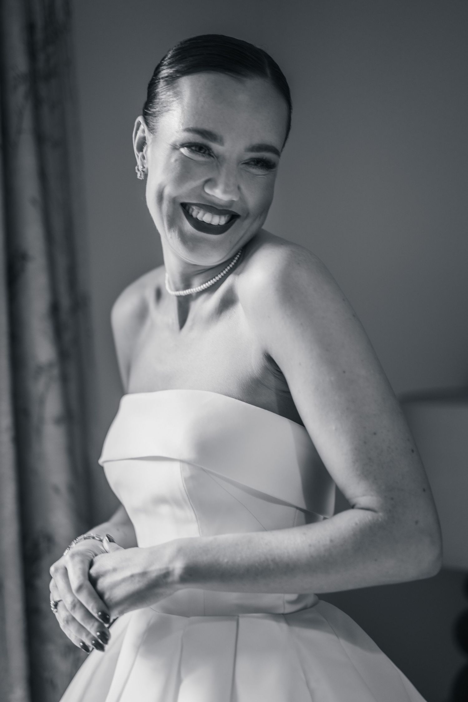 Radiant bride in strapless white wedding gown laughing joyfully, black and white bridal portrait.