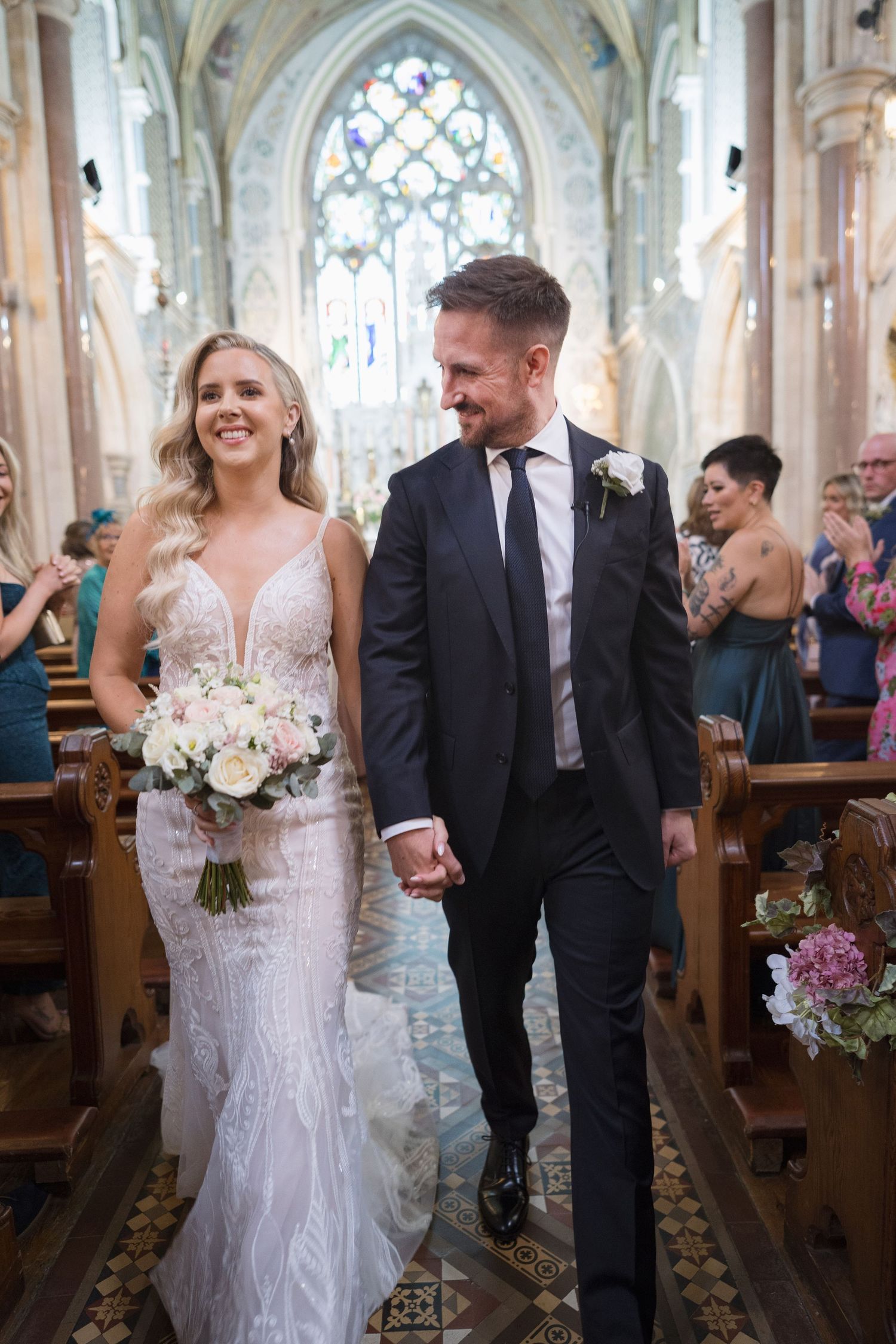 Bride and groom walking hand in hand down the aisle of a stunning Gothic cathedral.