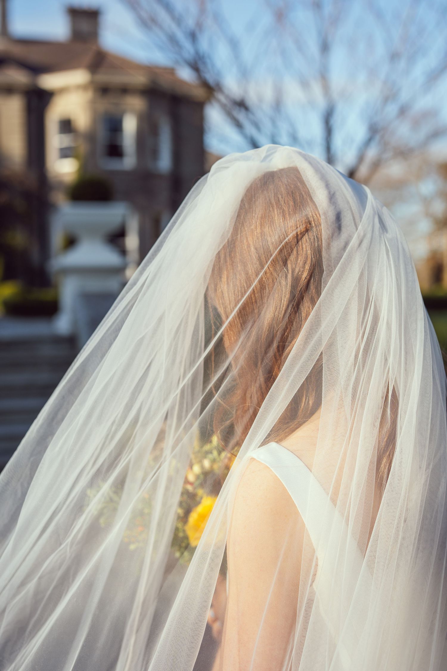 Bride with flowing veil covering her face stands outdoors at Tinakilly House wedding in Wicklow,