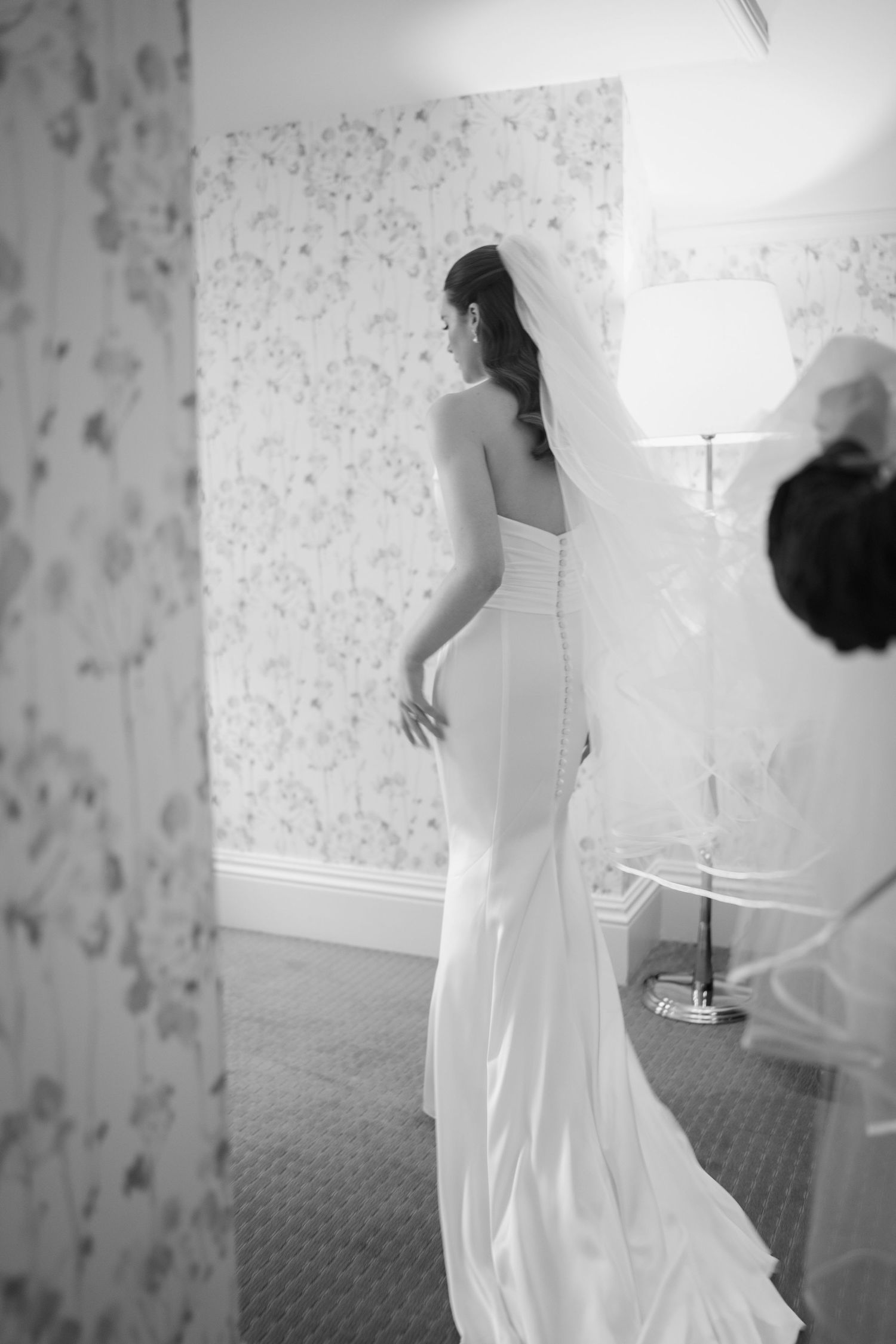 Bride in strapless fitted gown with long veil standing in black and white portrait at the Manor House Mount Juliet wedding Kilkenny.