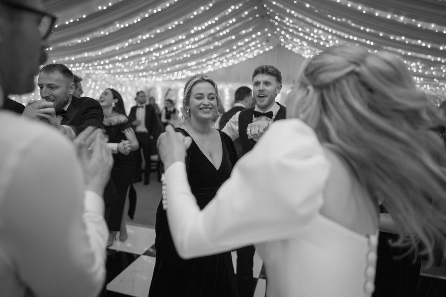 Bride dancing joyfully with wedding guests on the dance floor at the reception.